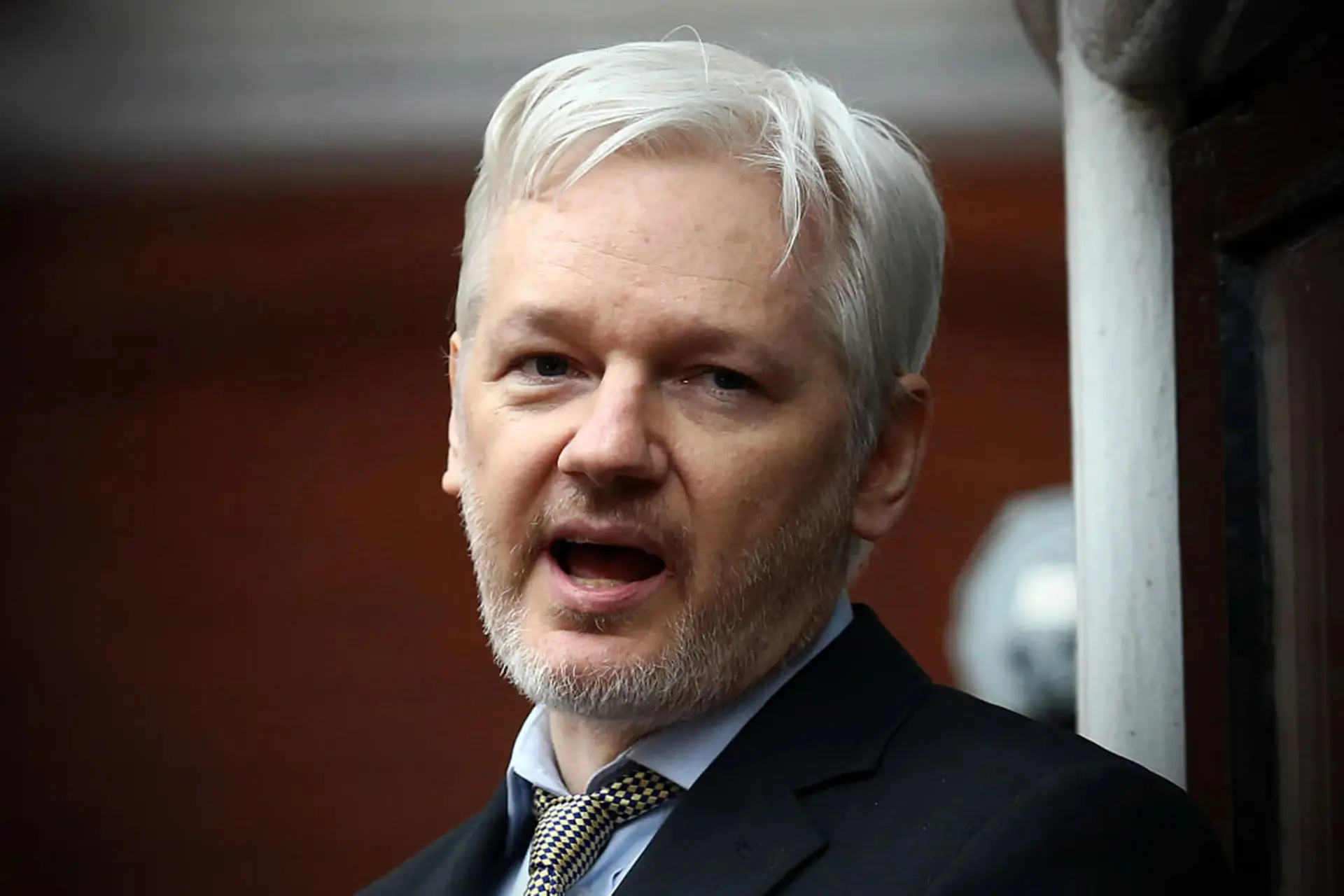 جولیان آسانژ (Julian Assange) با موهای سفید و کت تیره