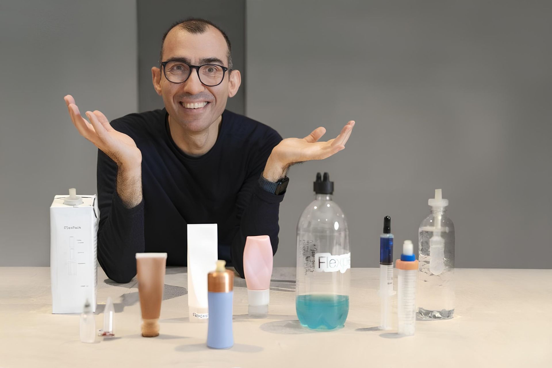 یک مرد جوان با دست‌های باز روی میز کنار چند محصول بهداشتی