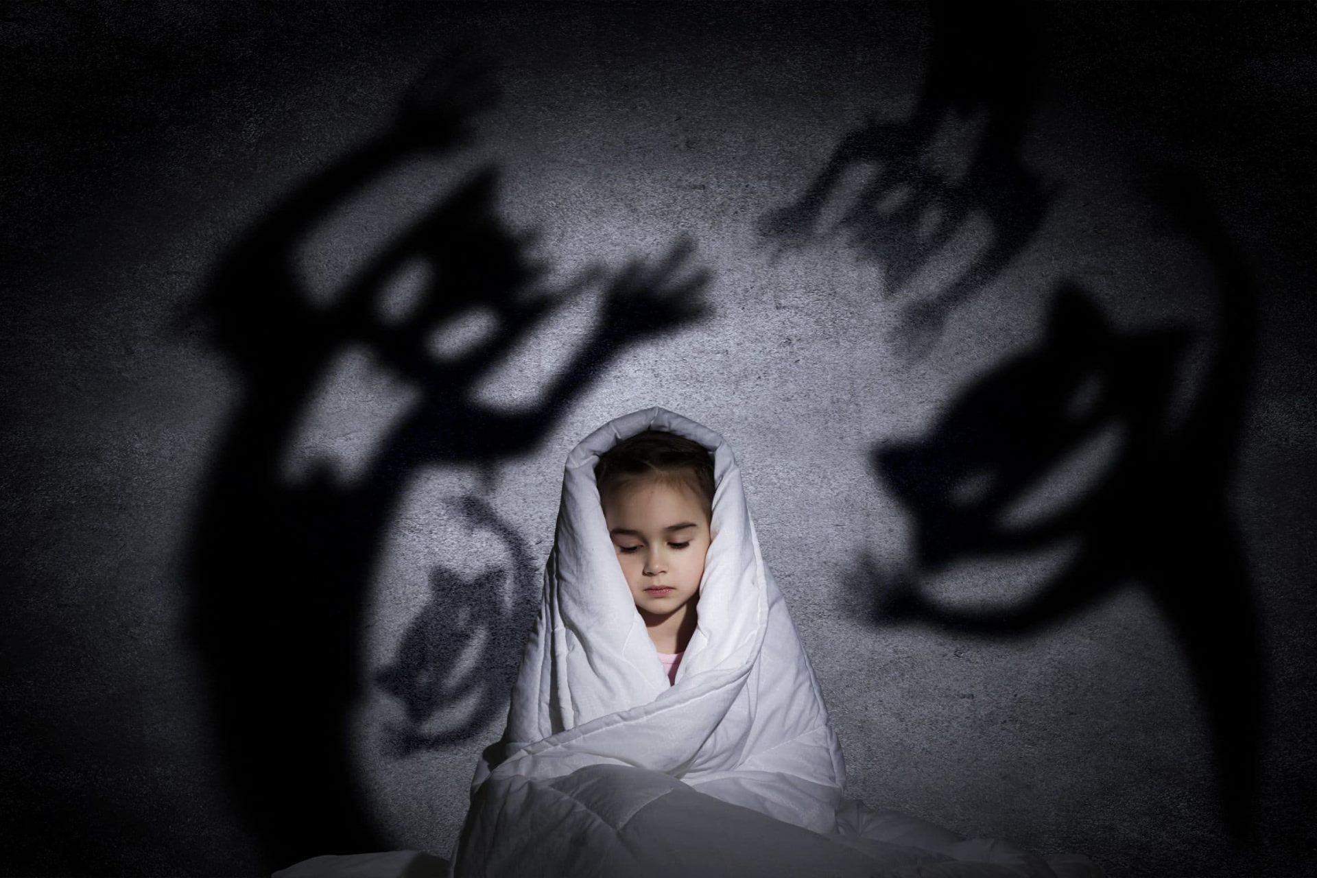 کودکی پیچیده در پتو با سایه‌های ترسناک اطرافش