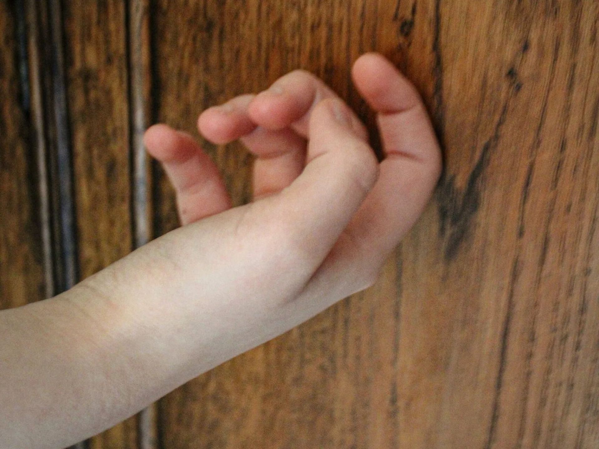 دستی در حال ضربه زدن آرام به در چوبی 