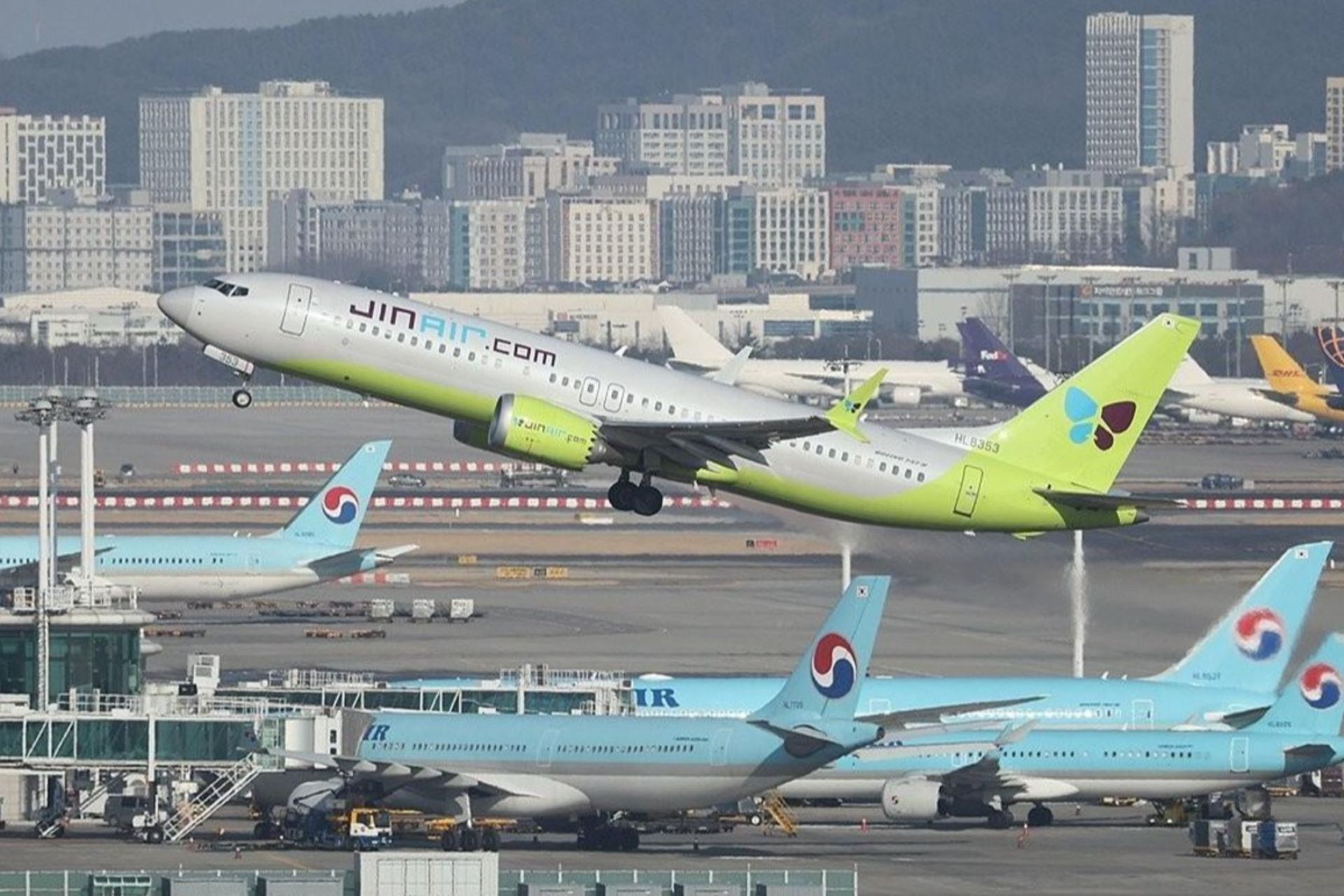 پرواز هواپیما در پس‌زمینه‌ی فرودگاه