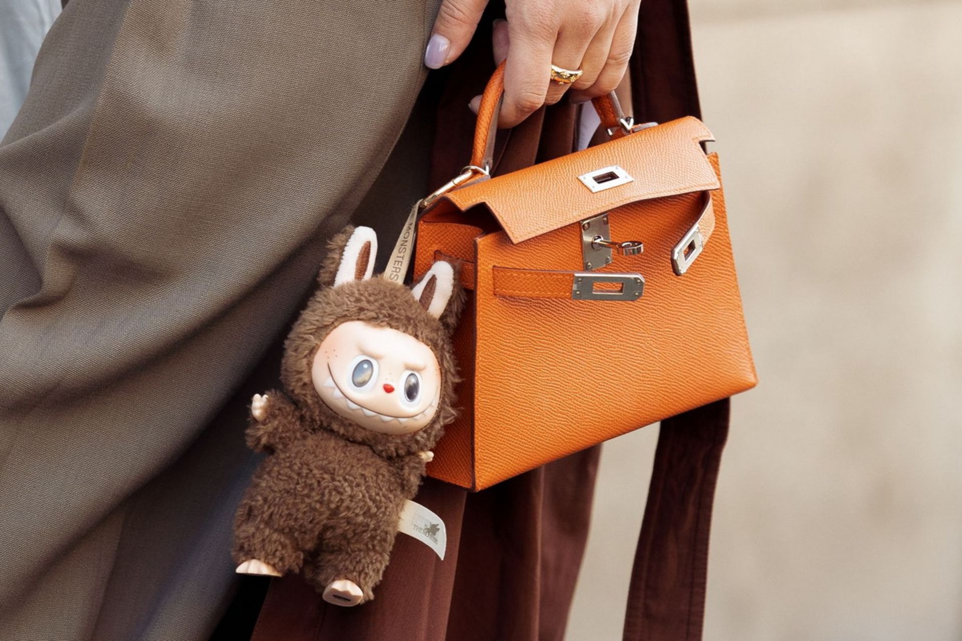 زنی با کیف دستی چرم و آویز عروسک لبوبو