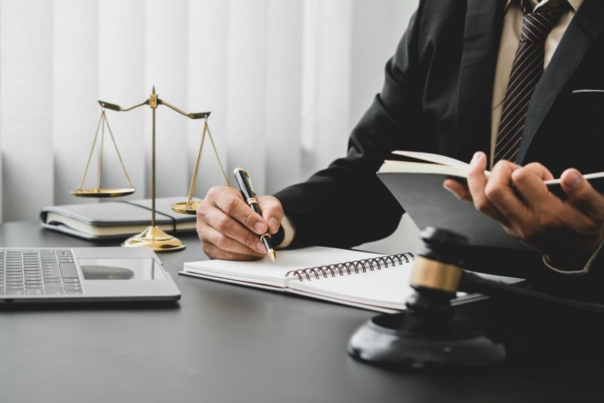 شخصی در حال نوشتن روی دفترچه روی میز با میزان