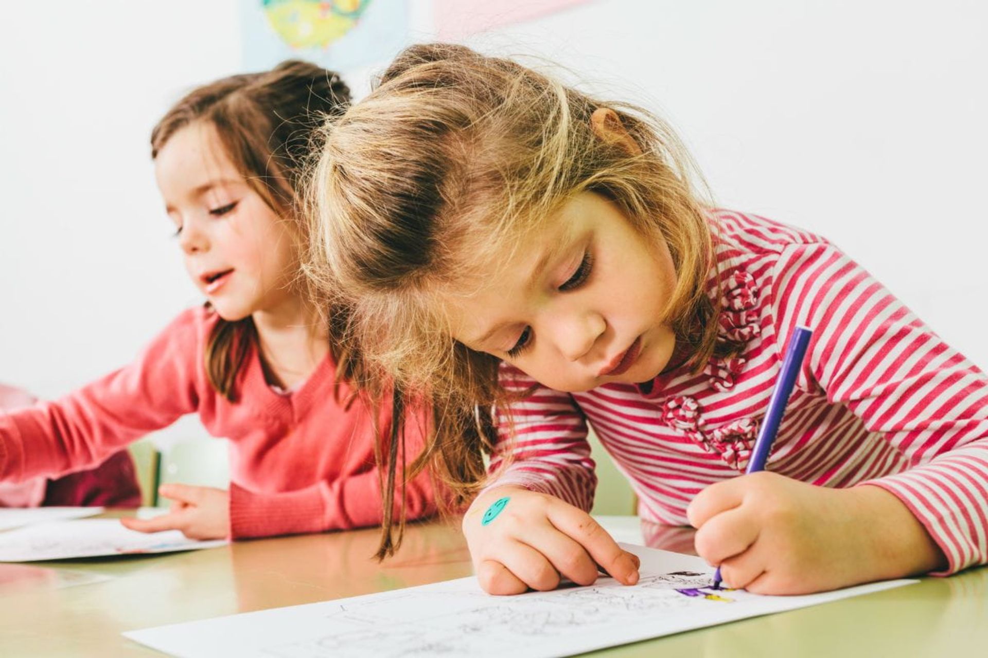 دختر خردسال درحال نقاشی‌کشیدن با دست چپ خود است