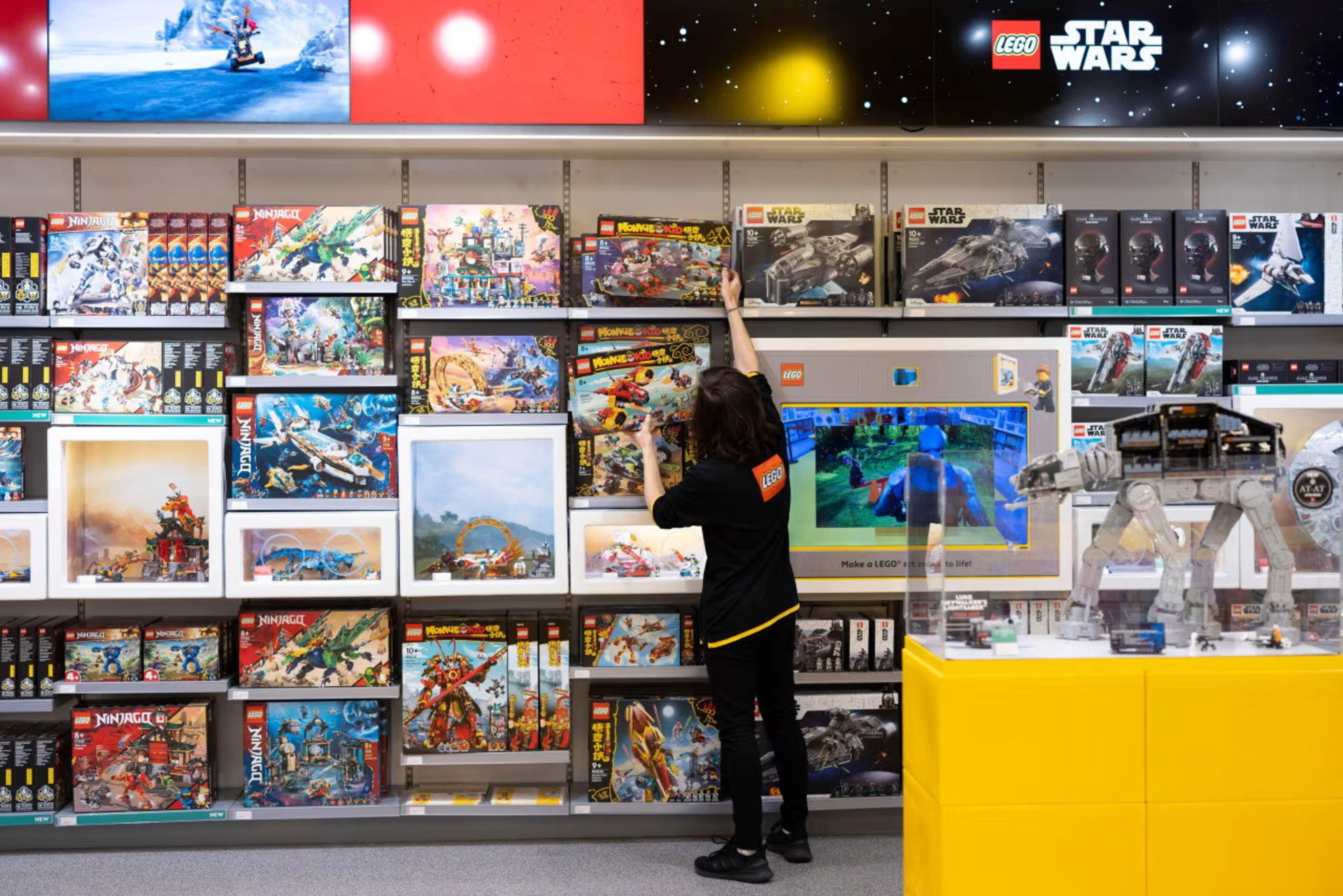 کودکی در حال برداشتن جعبه لگو از قفسه