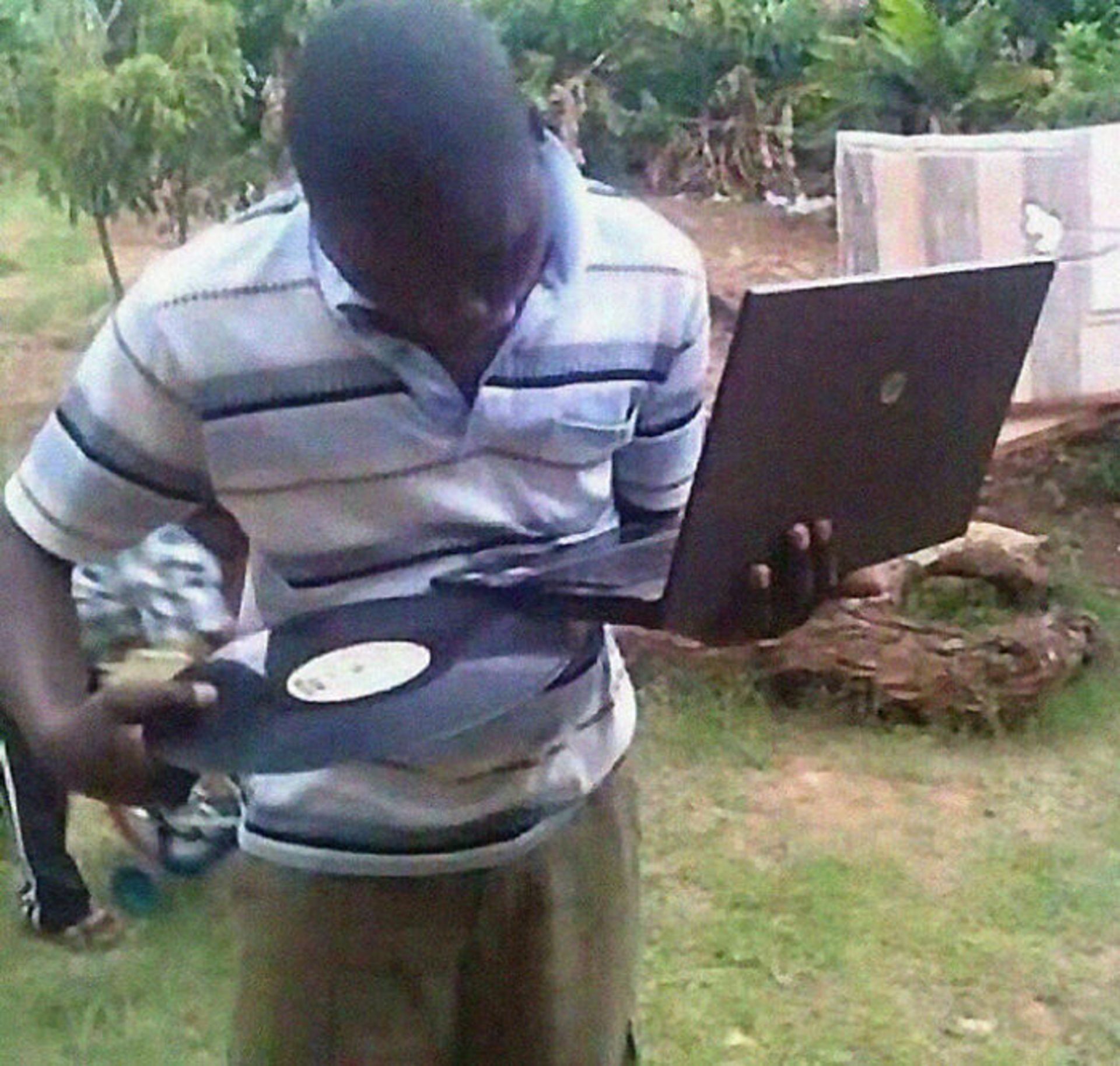 مرد سیاه‌پوست در حال جا دادن صفحه گرام در درایو DVD لپ‌تاپ