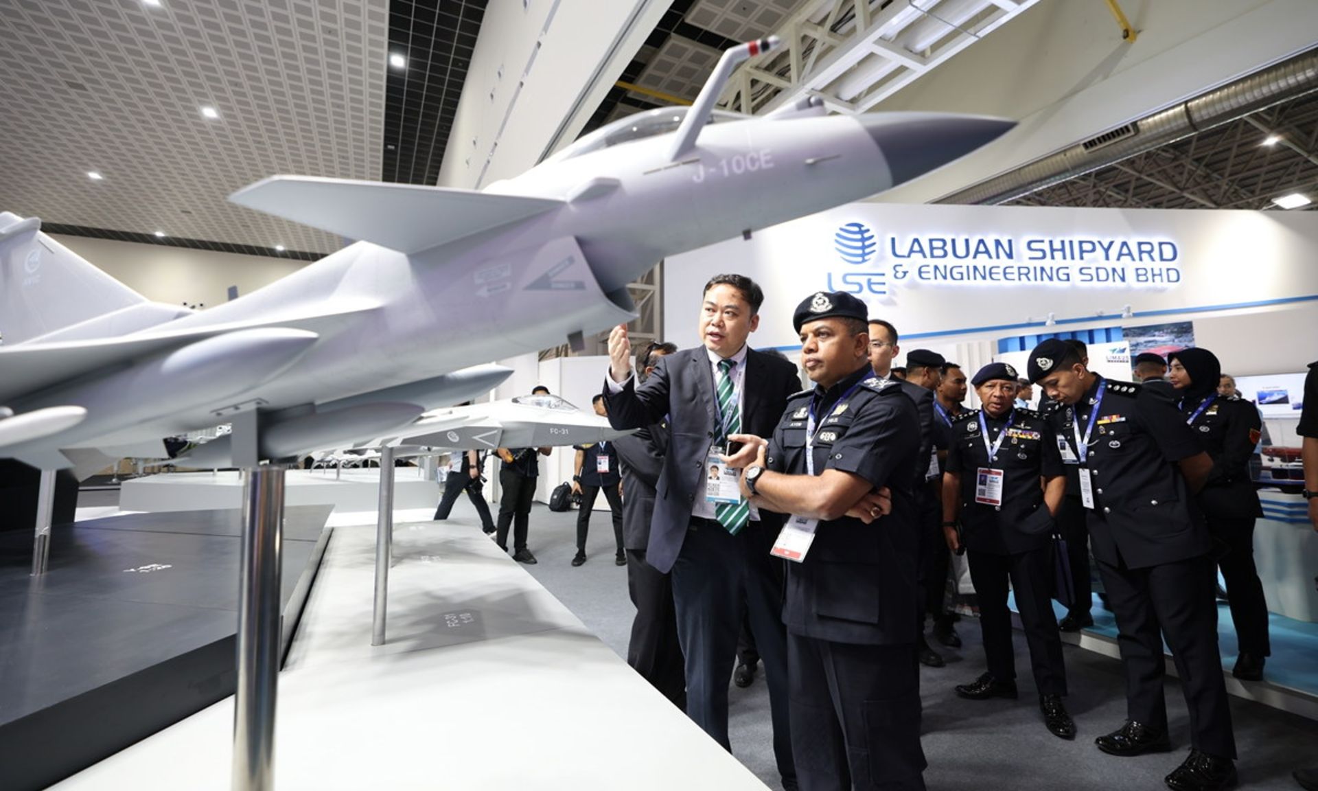 بازدیدکنندگان نمایشگاه LIMA 2025 در حال تماشای ماکتی از جنگنده J-10CE چین