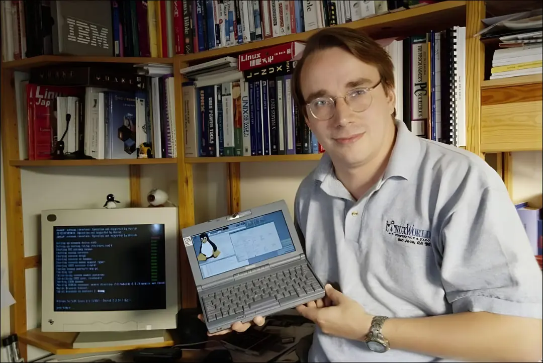  لینوس توروالدز و لینوکس (Linux) روی نمایشگر یک لپ‌تاپ قدیمی در کنار مانیتور کامپیوتر