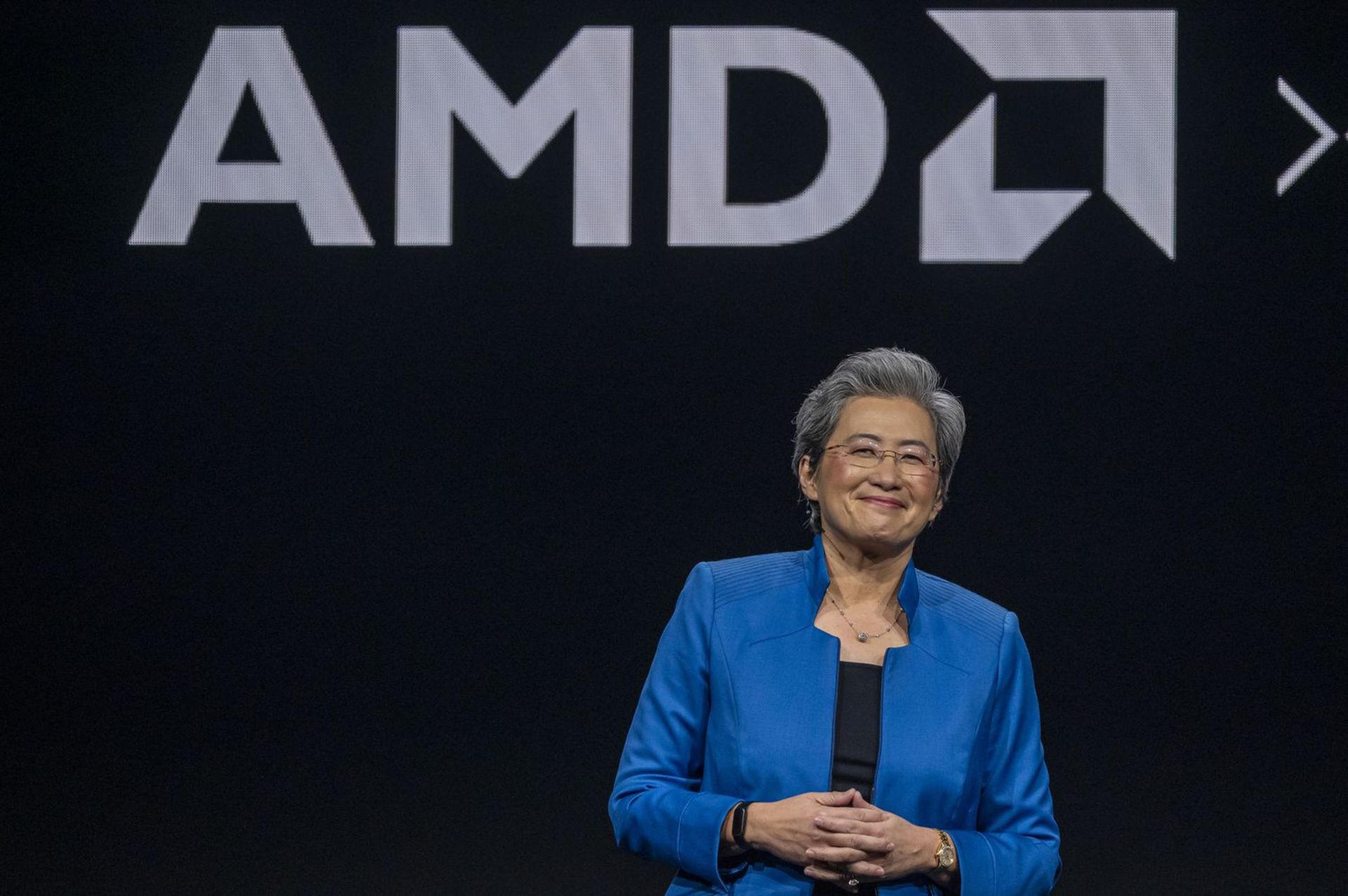 لیسا سو مدیرعامل AMD لبخندزنان روی صحنه با لوگو AMD‌ پشت سر او