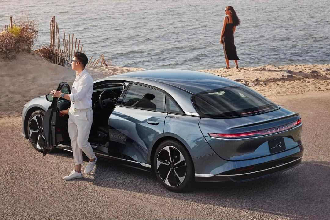 مرد و زن جوان در کنار خودرو لوسید Lucid Air Pure RWD در ساحل
