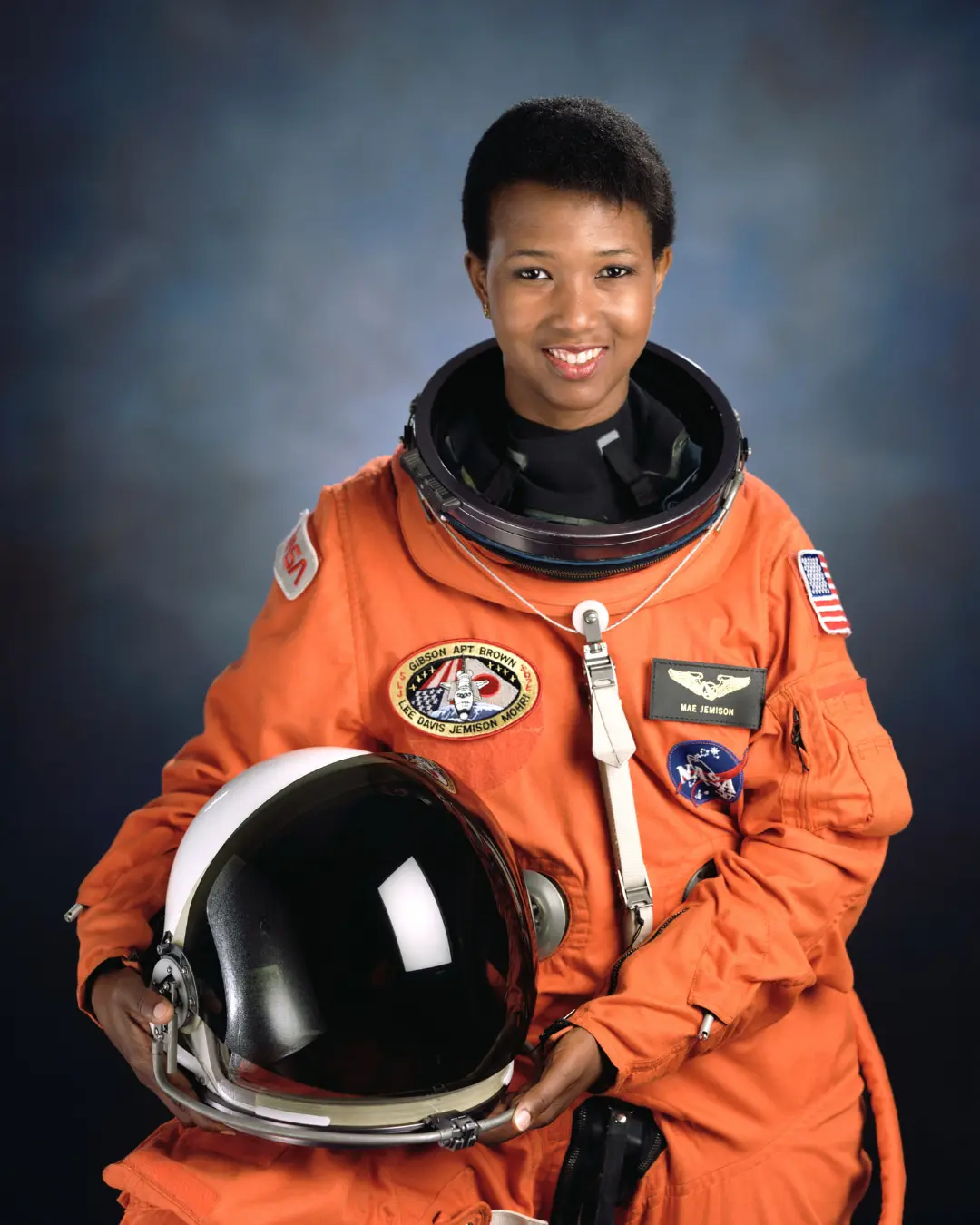 می جمیسون (Mae Jemison) فضانورد سیاه‌پوست با لباس نارنجی و کلاه ایمنی
