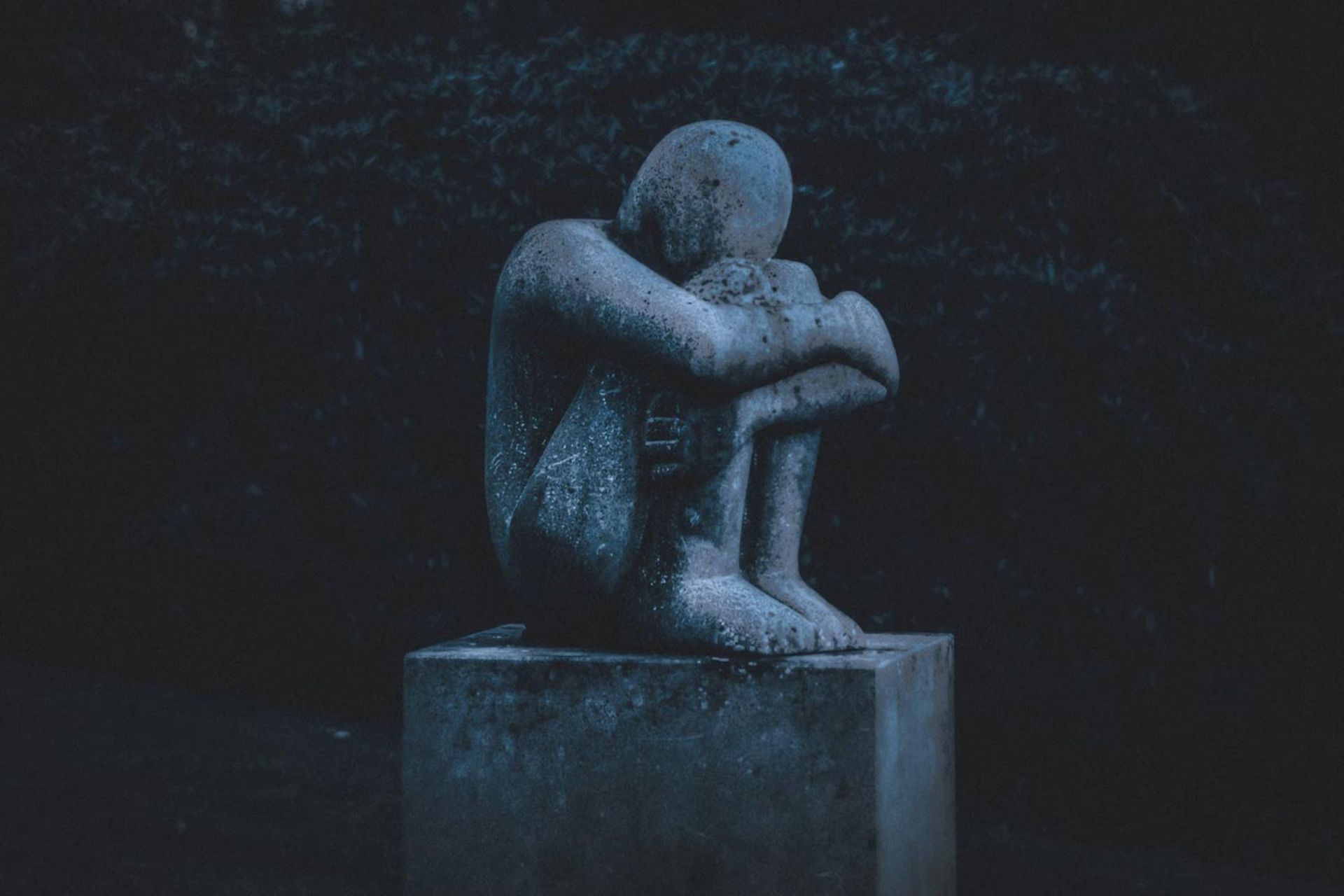 مجسمه‌ی مردی نشسته که زانوی خود را بغل گرفته