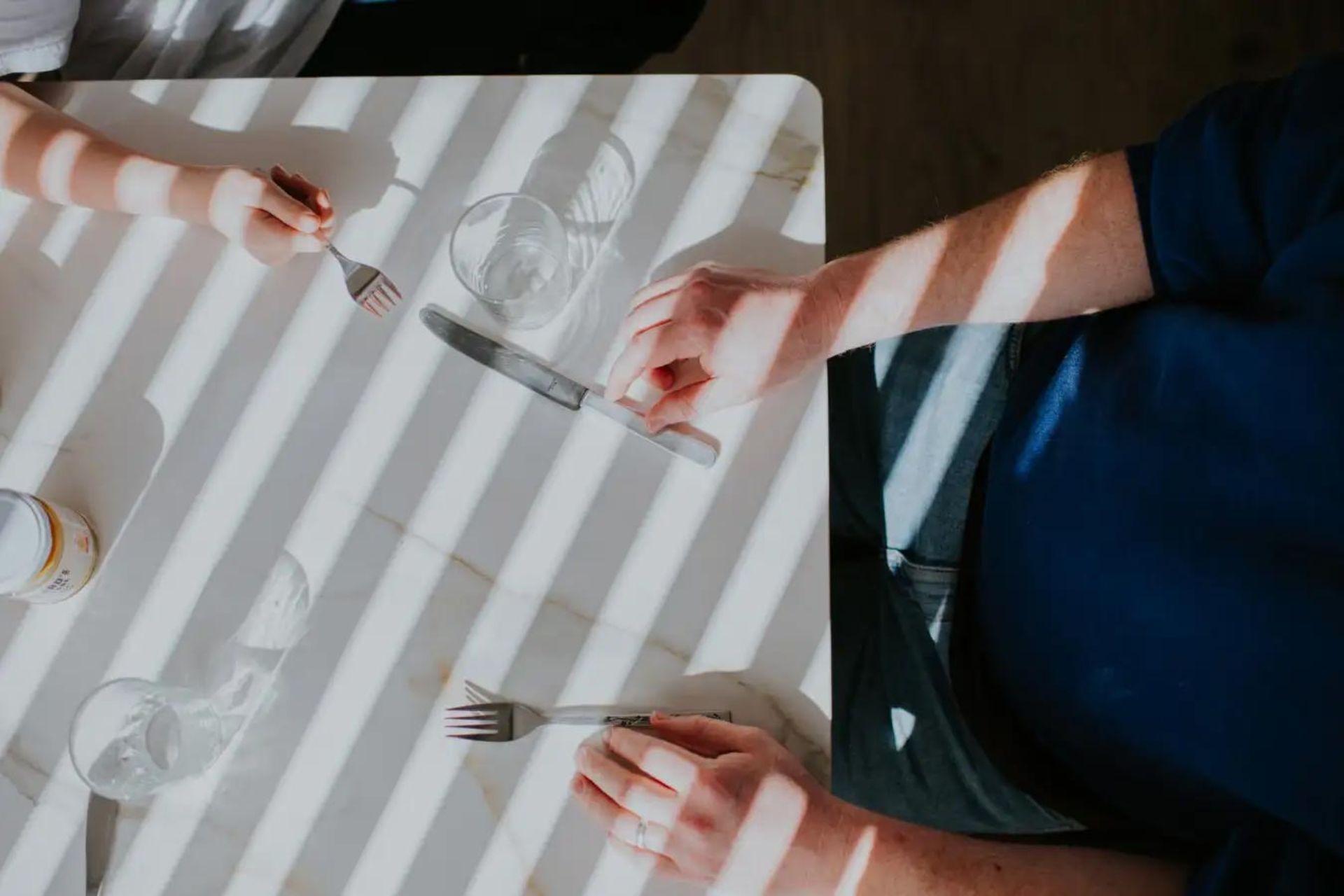 نمای بالا از مردی دارای اضافه‌وزن که پشت میز غذاخوری نشسته است