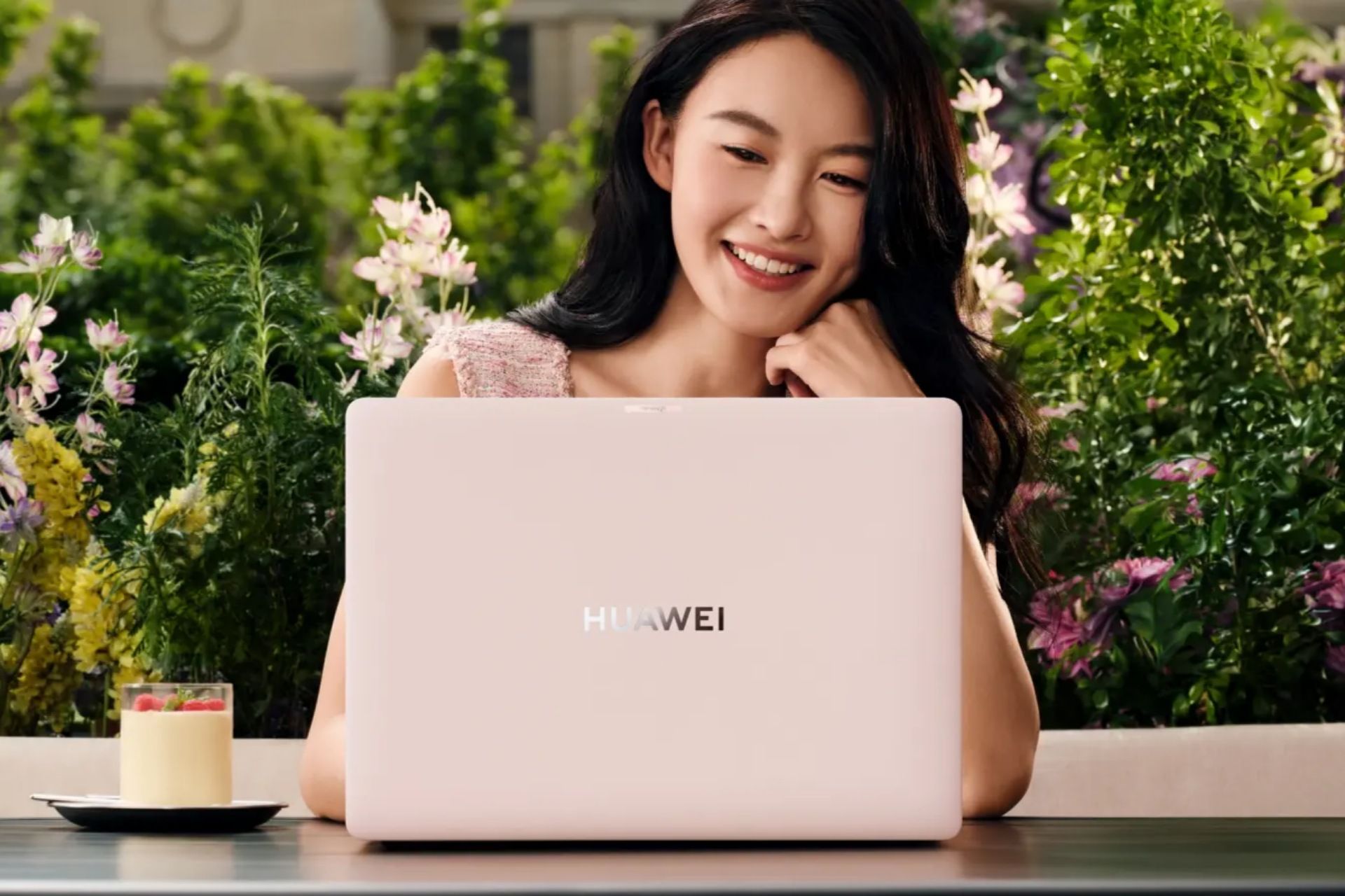 زن جوان درحال کار با هواوی میت‌بوک پرو صورتی