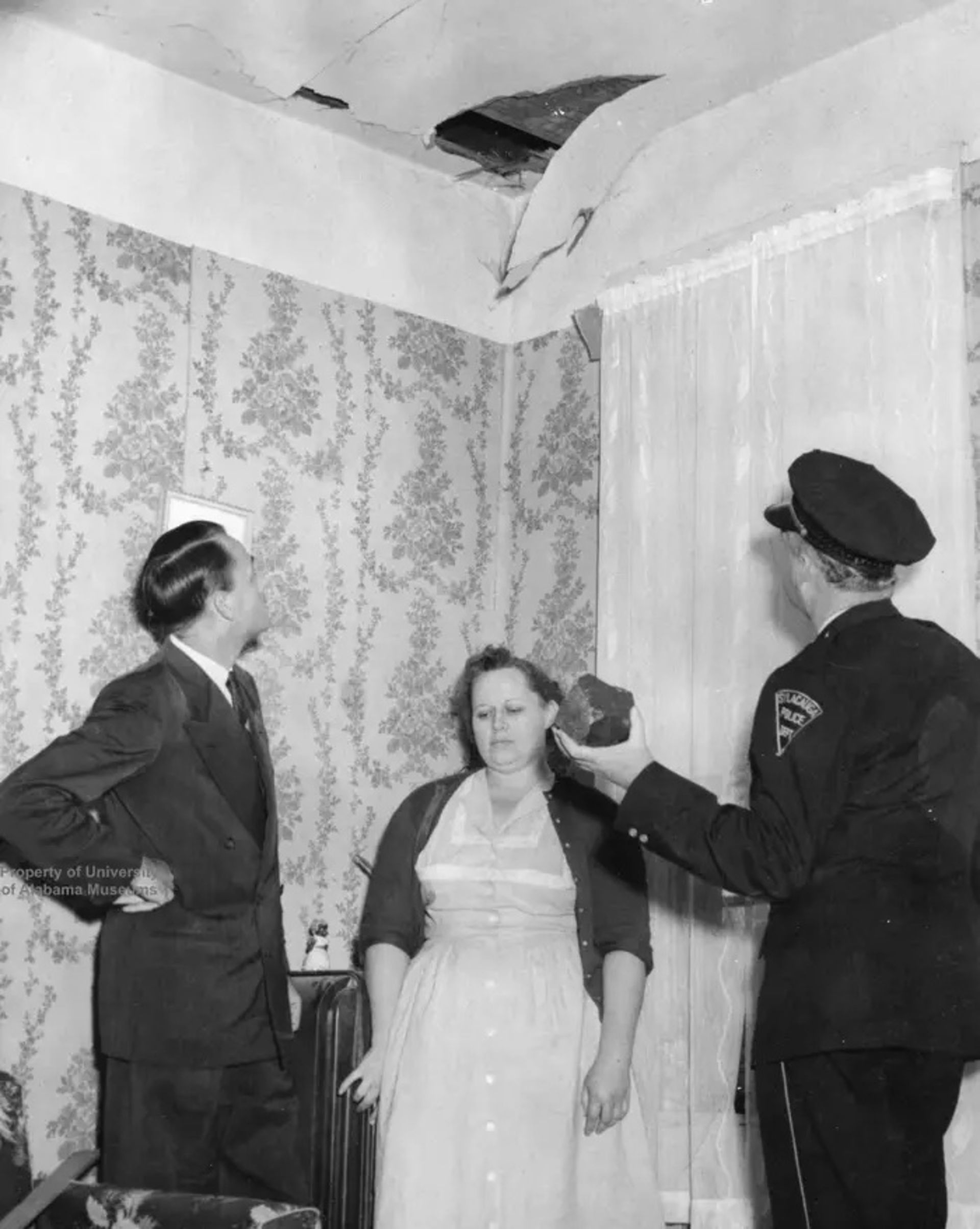 افسر پلیس و یک مرد در کنار یک زن زیر سقف سوراخ ایستاده‌اند