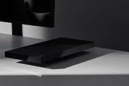 مینی پی‌سی (Mini PC) مشکی رنگ مایکروسافت با بدنه بافت‌دار روی میز