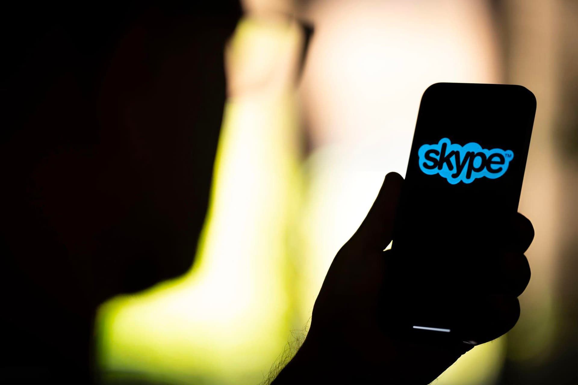 لوگو اسکایپ / Skype روی آیفون در دست در تاریکی