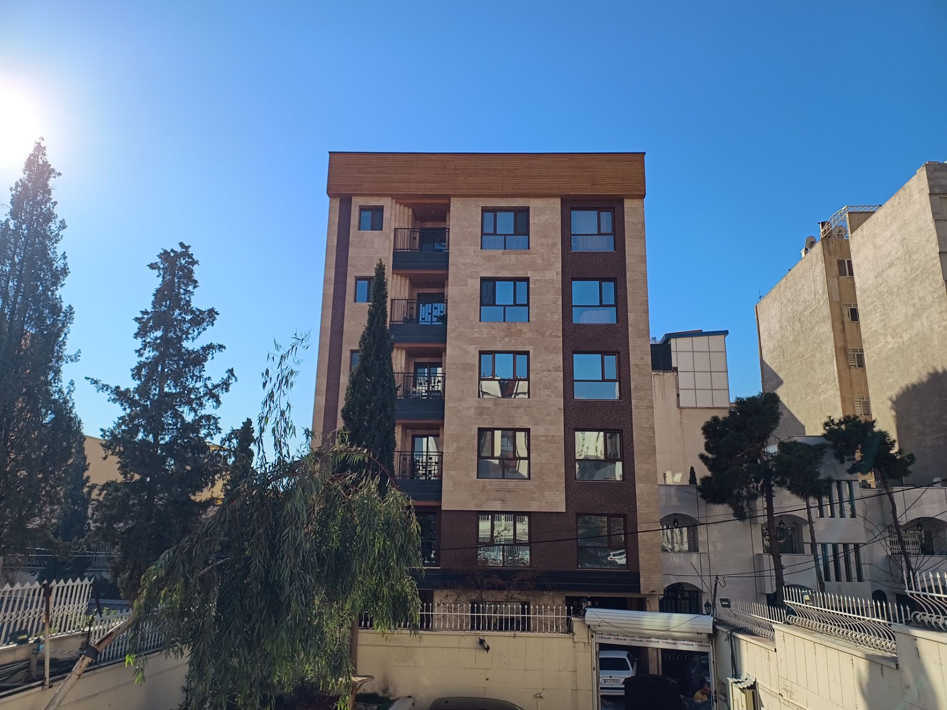 ساختمان در روبرو و خورشید در سمت چپ تصویر