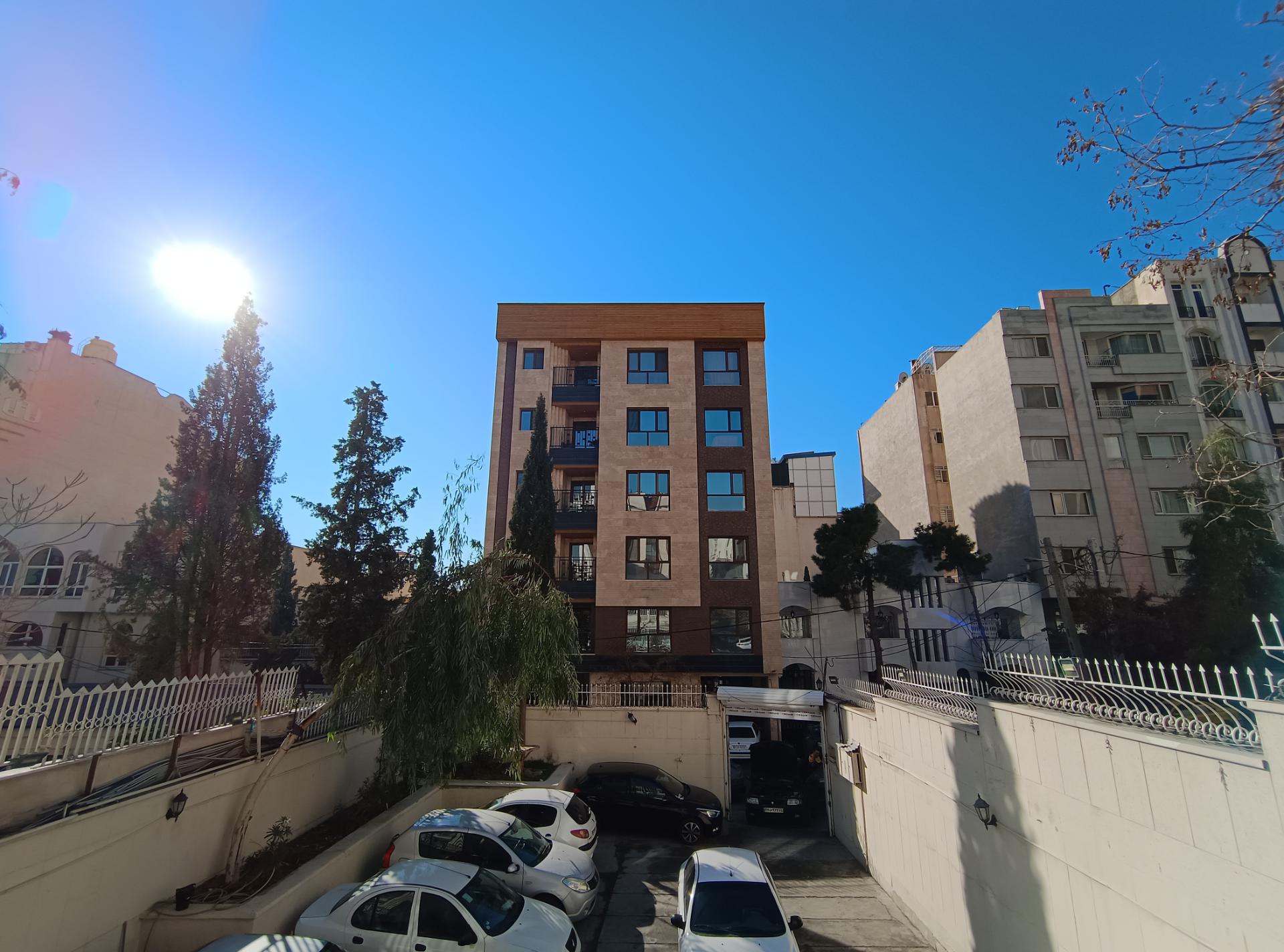 ساختمان در وسط و درختان و خورشید در سمت چپ