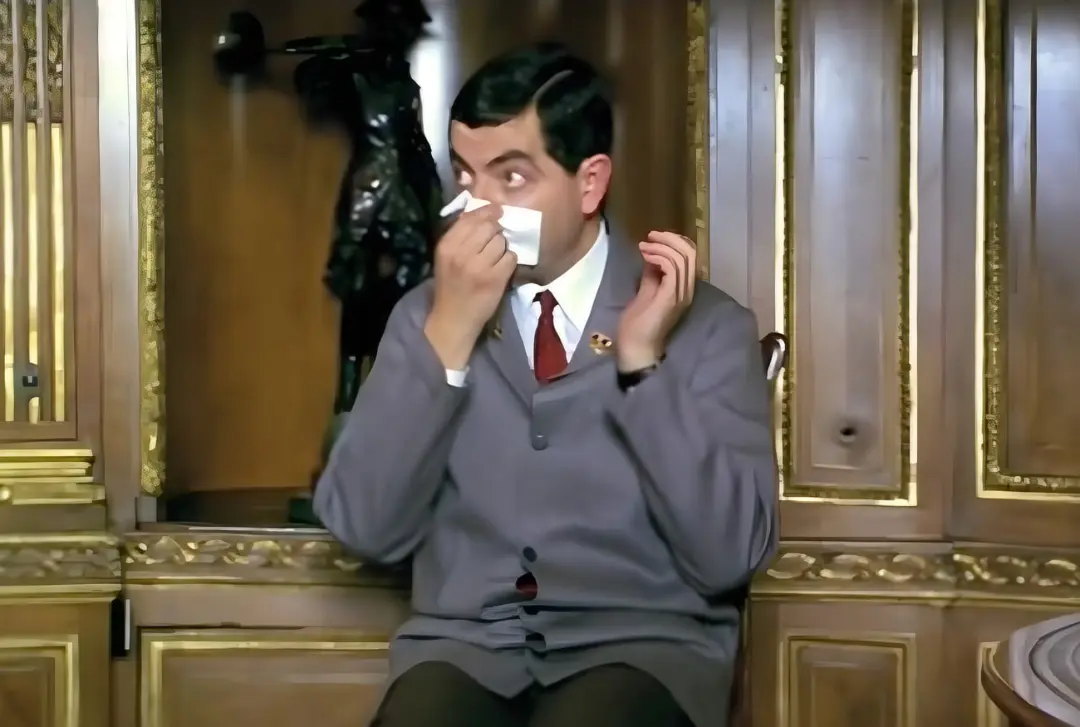مستر بین (Mr. Bean) با دستمال کاغذی در حال فین کردن در یک فضای مجلل