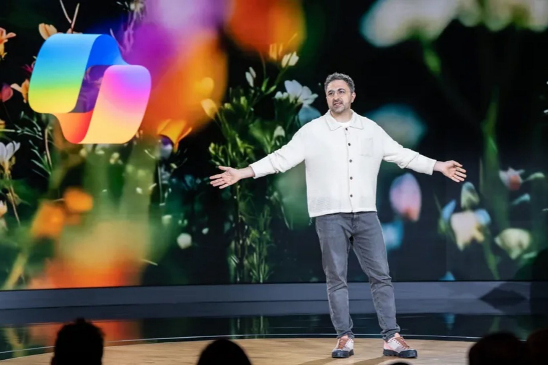 مصطفی سلیمان، رهبر تیم هوش مصنوعی مایکروسافت، ایستاده در کنار لوگوی کوپایلت