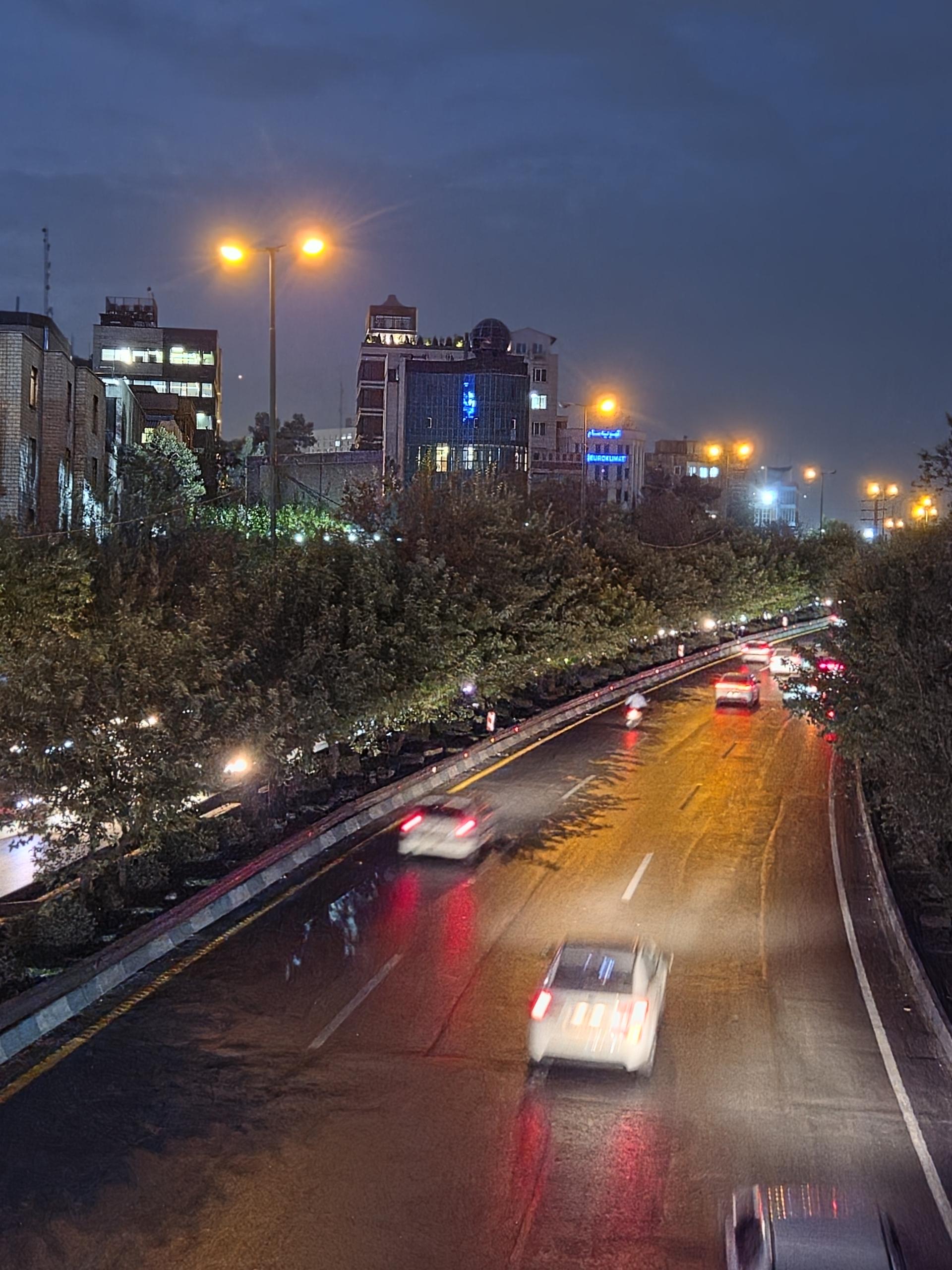 جاده پرتردد شهری در شب با رد نور خودروها و چراغهای خیابان