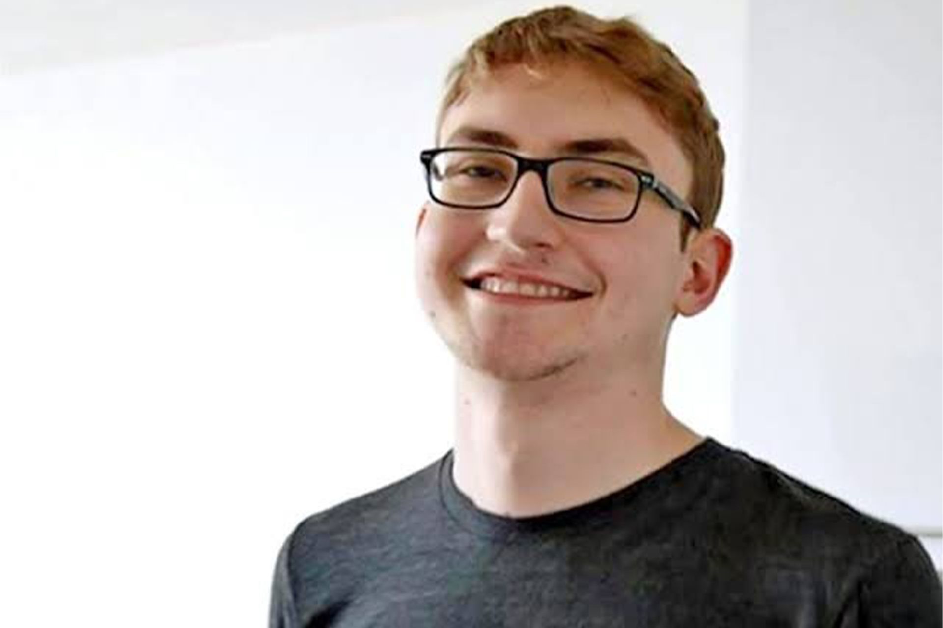 چهره‌ی یک پسر جوان با عینک در حال لبخند