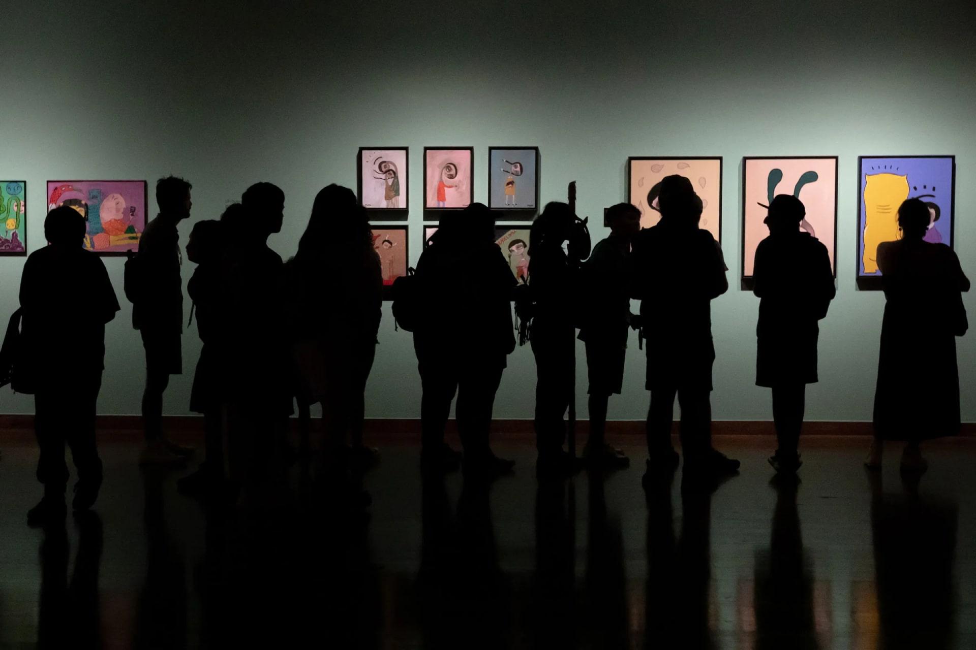 گروهی در حال تماشای تابلوهای نقاشی در گالری هنری