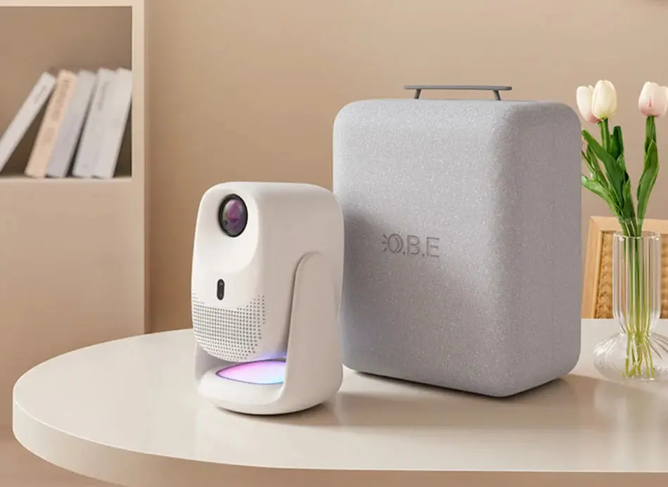 پروژکتور سفید رنگ OBE C5 Pro در کنار اسپیکر خاکستری