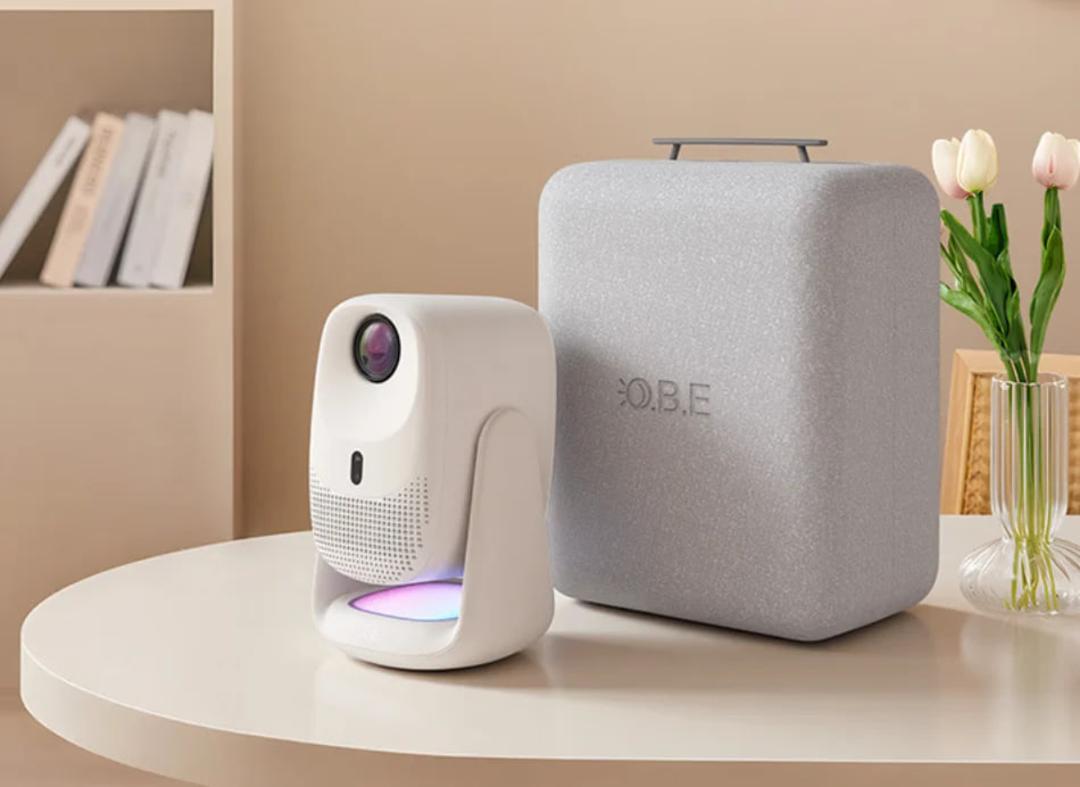 پروژکتور سفید رنگ OBE C5 Pro در کنار اسپیکر خاکستری