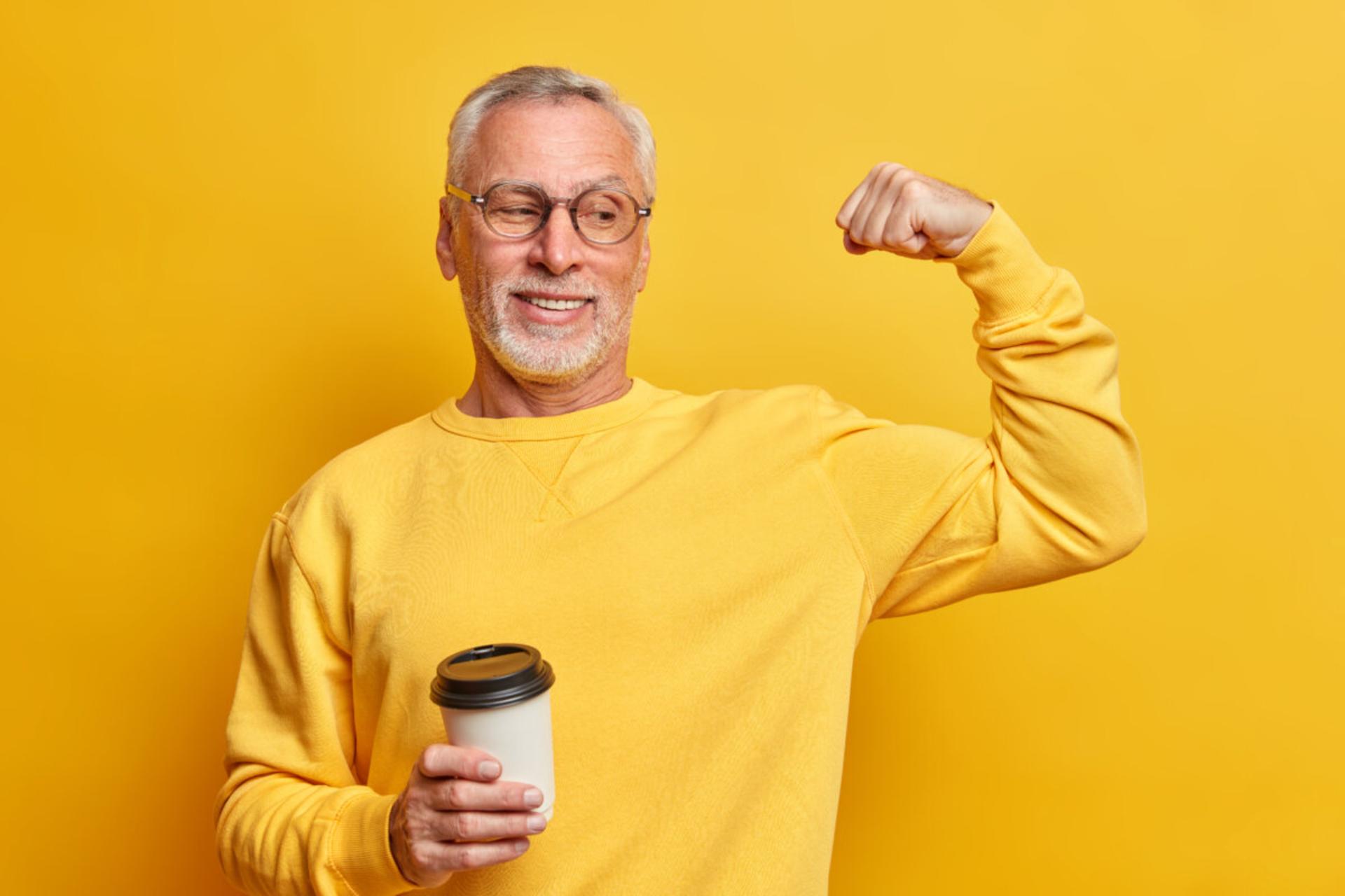 مرجع متخصصين ايران مرد مسن با لباس زرد و قهوه در دست در حال كشيدن عضلات زمينه زرد