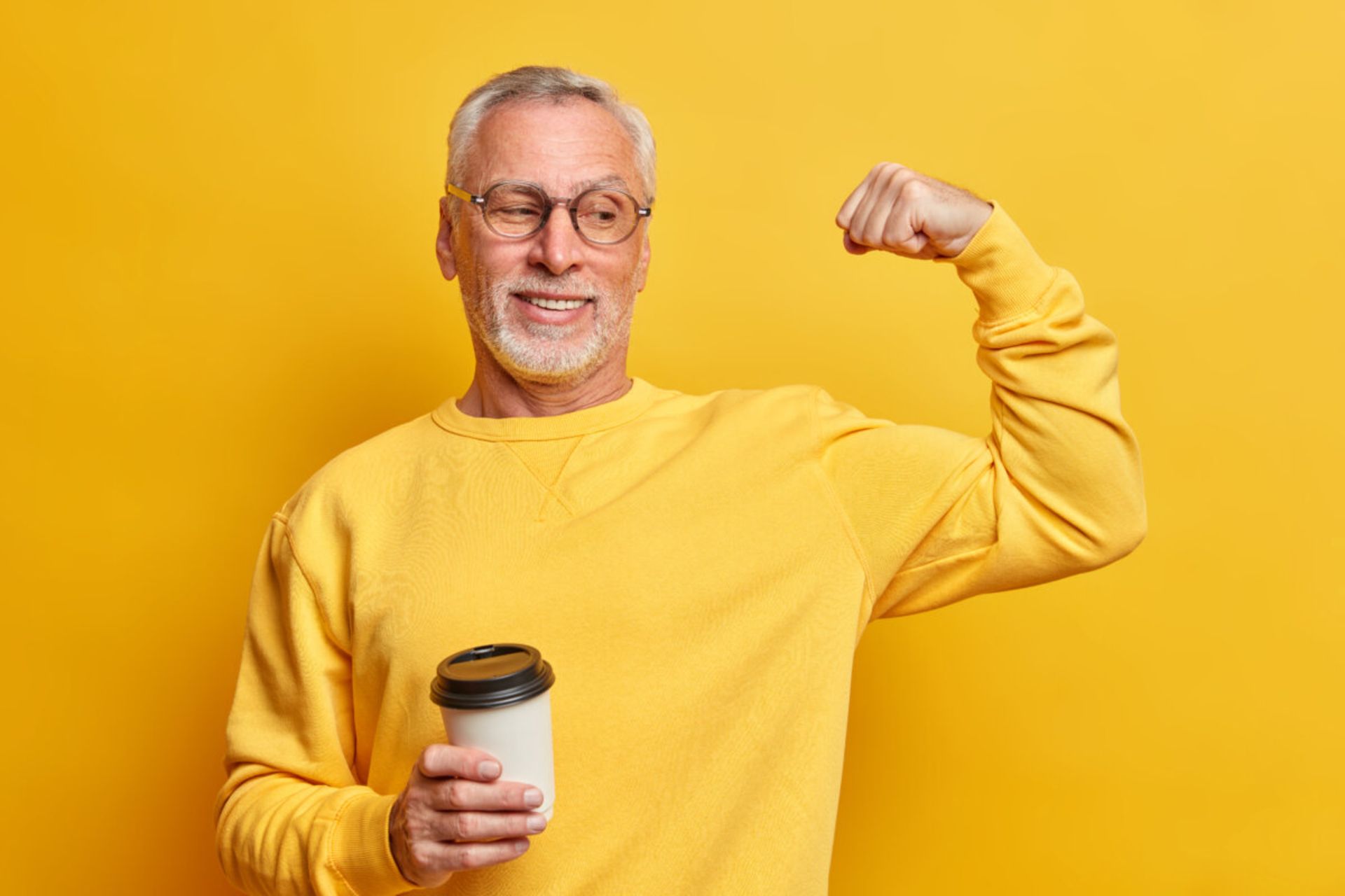 مرد مسن با لباس زرد و قهوه در دست در حال کشیدن عضلات زمینه زرد