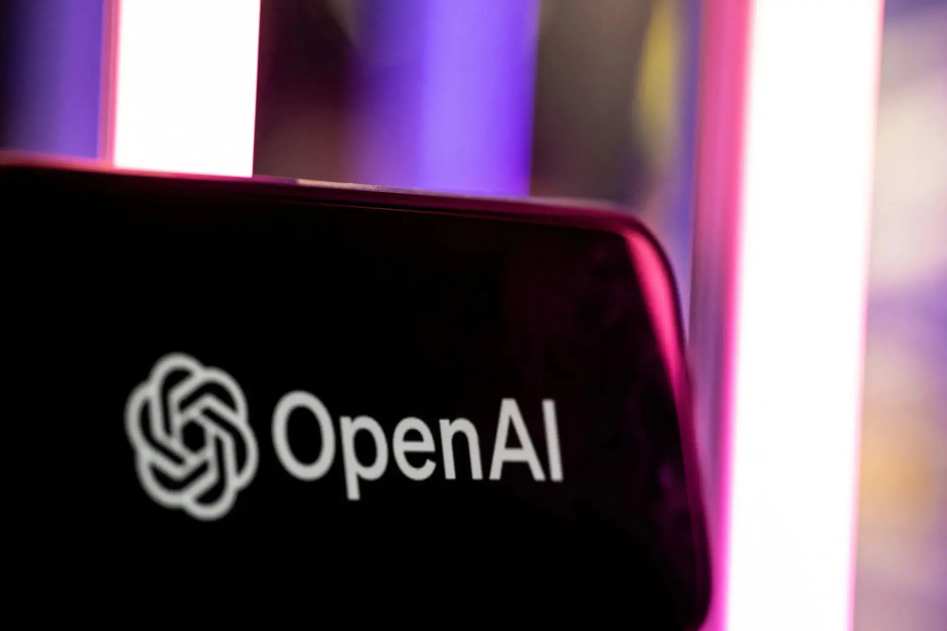 لوگوی سفید شرکت OpenAI روی صفحه نمایش سیاه گوشی هوشمند