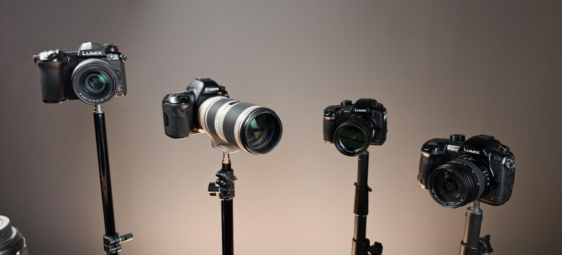 دوربین‌های دیجیتال مختلف از برندهای لومیکس (Lumix) و کانن (Canon) روی سه پایه