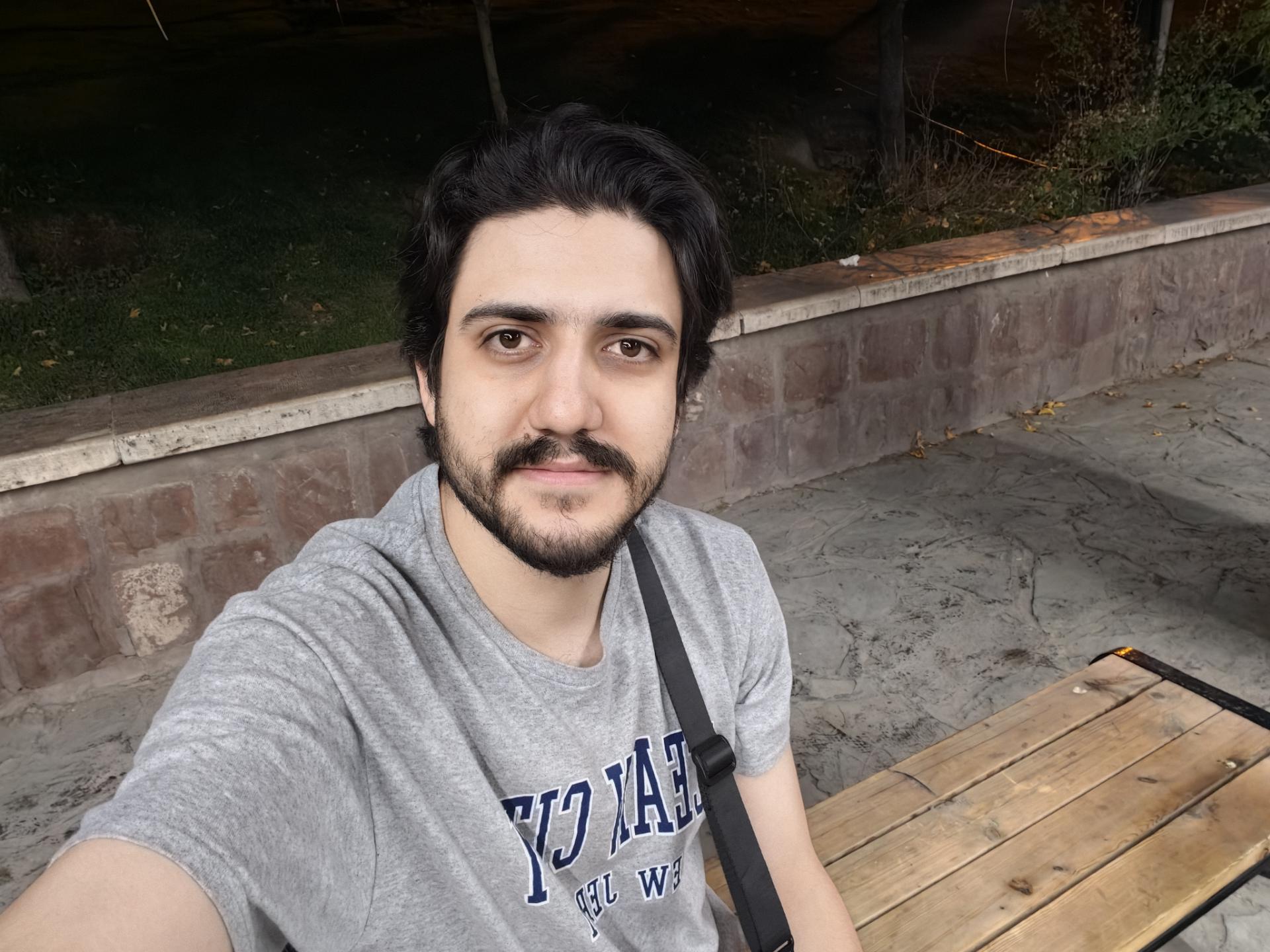 مرد جوان با تیشرت خاکستری در فضای باز پارک