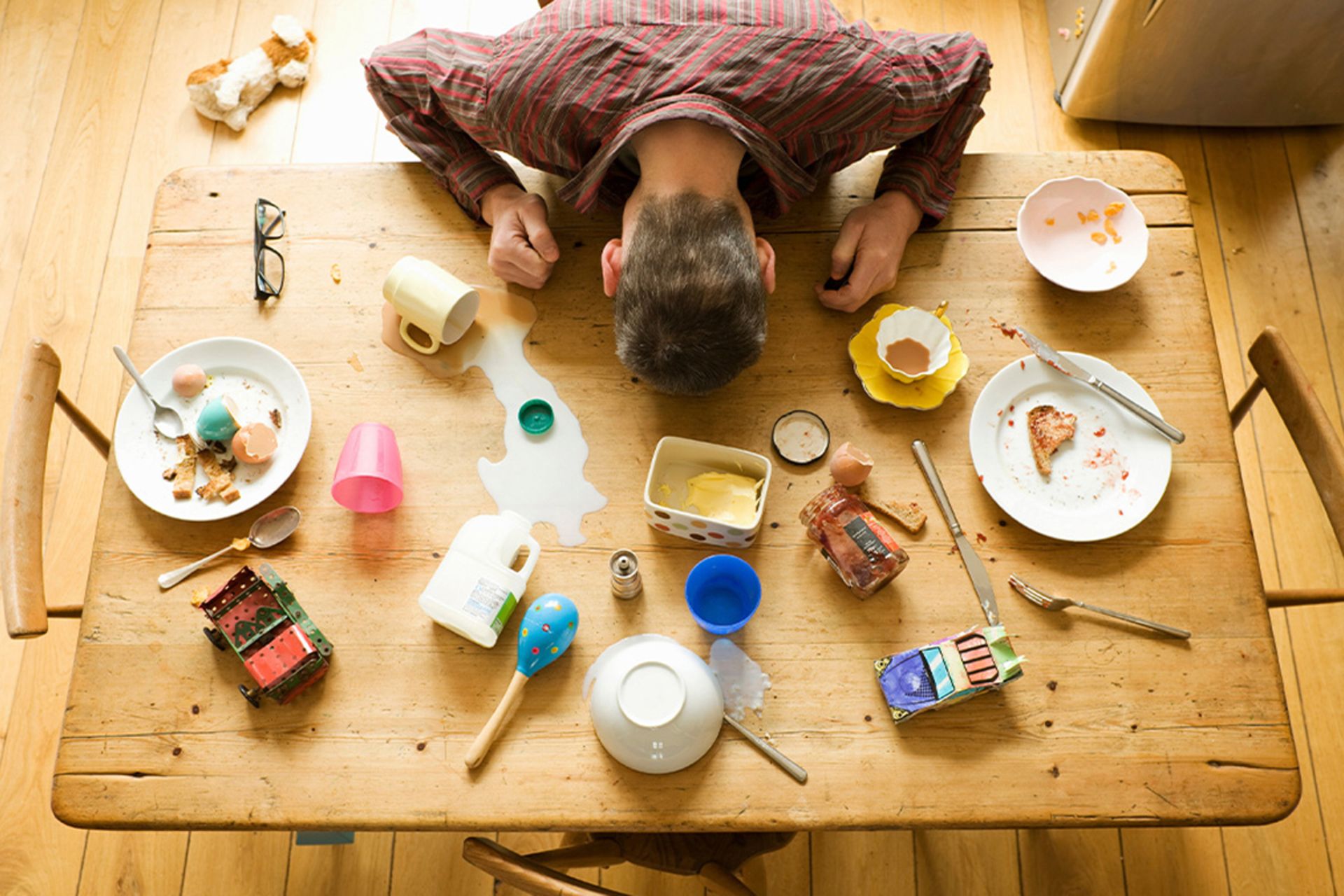 مردی که سرش را روی یک میز شلوغ و به هم ریخته قرار داده است