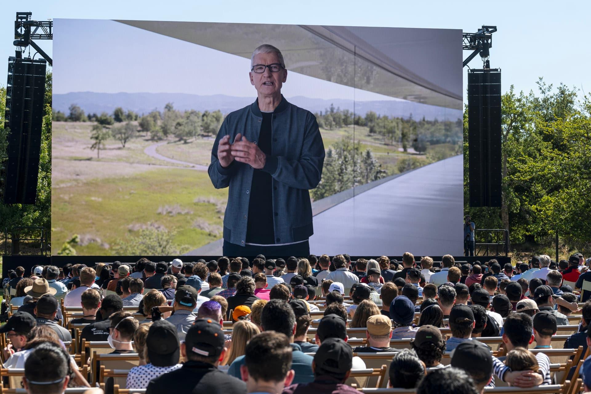 مردم در حال تماشا تیم کوک / Tim Cook روی نمایشگر WWDC 2022 اپل