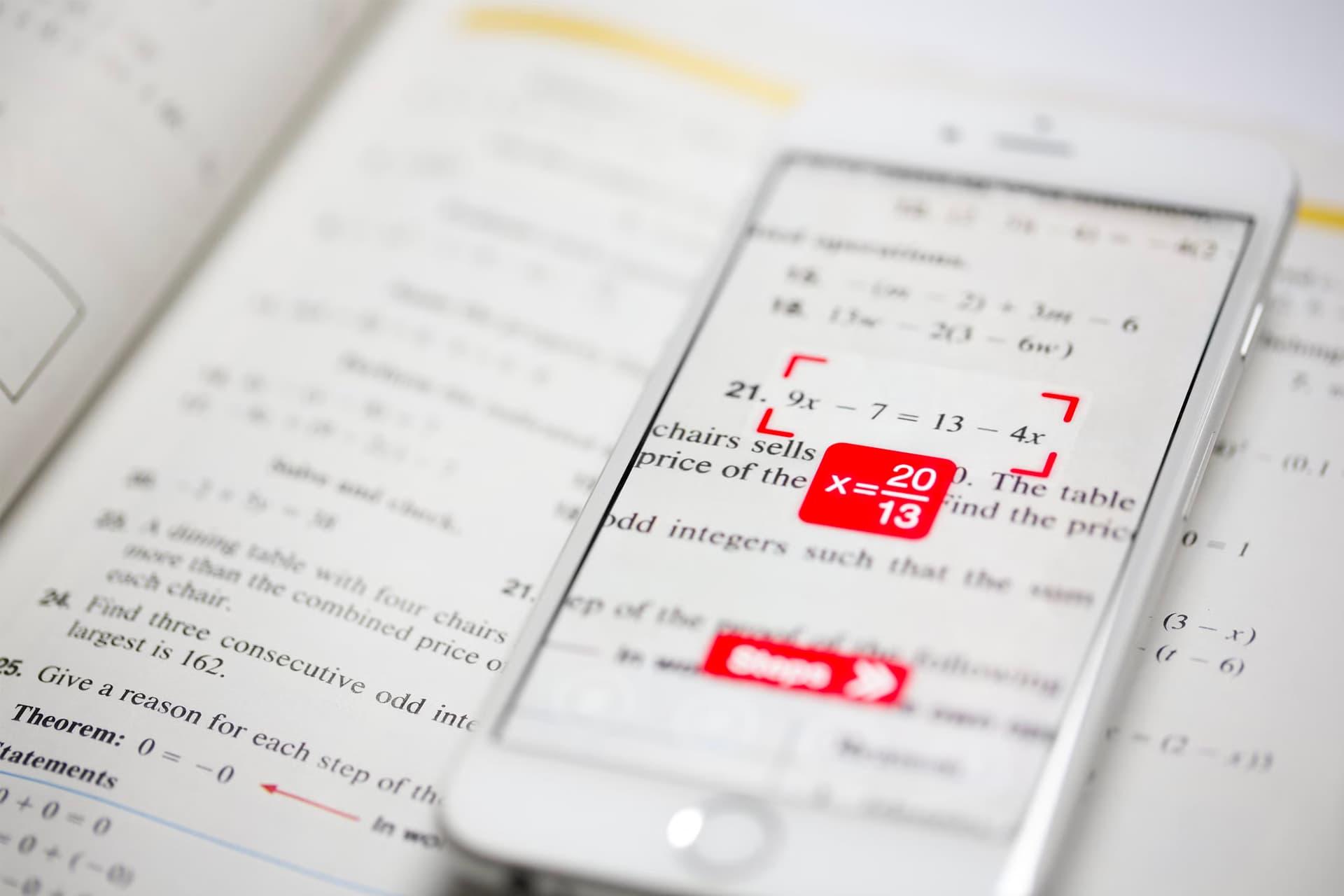 اپلیکیشن PhotoMath در آیفون ۸ روی کتاب