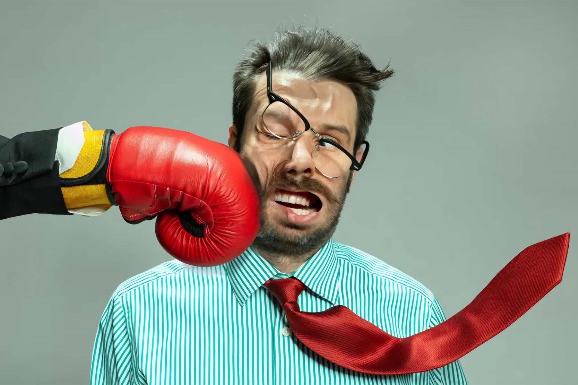 مرد جوان با عینک کج شده و کراوات قرمز با چهره درهم مورد حمله پنجه بوکس قرمز