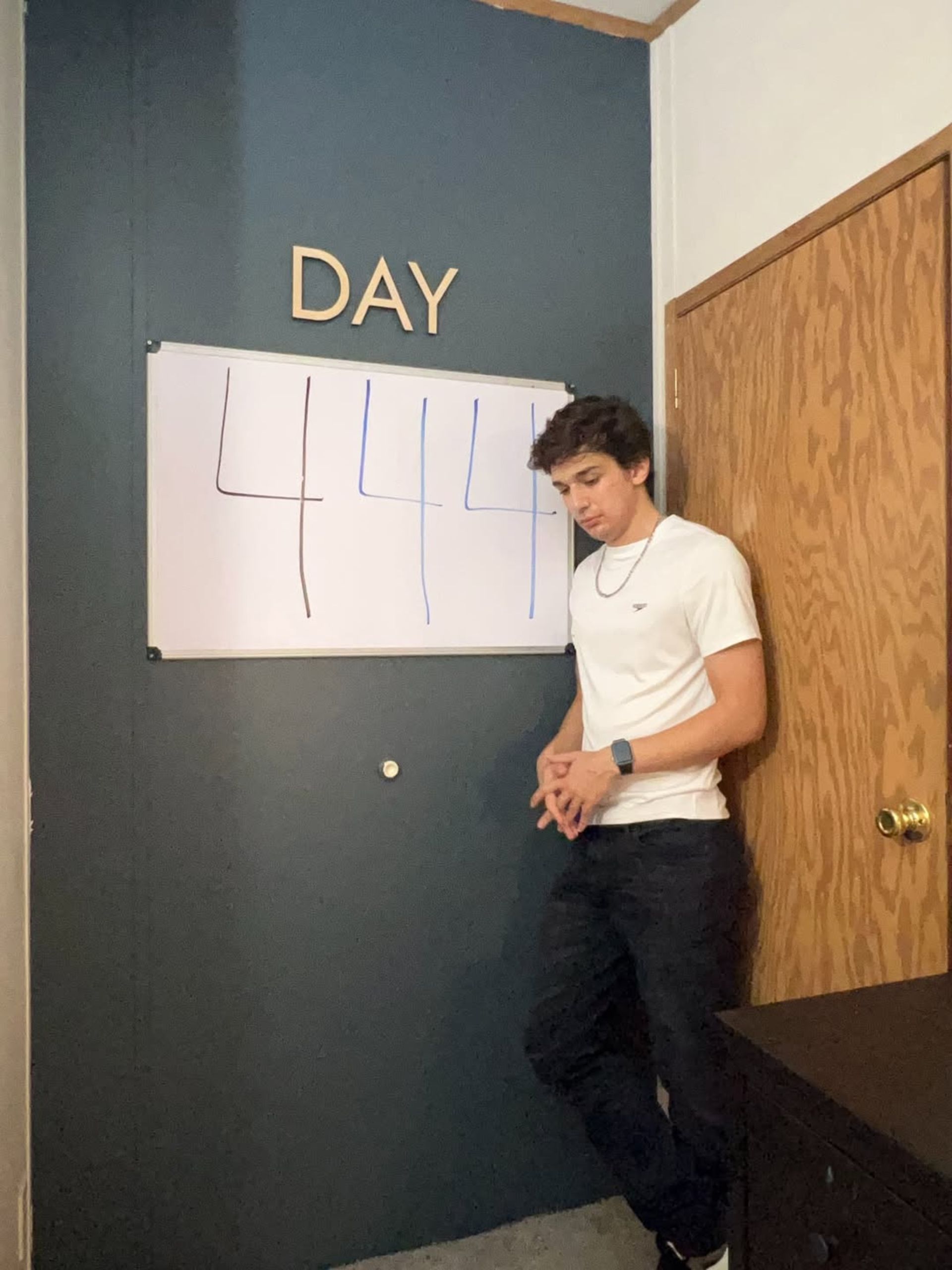 یک پسر جوان با لباس سفید در حال نمایش عدد روی تخته وایت‌برد