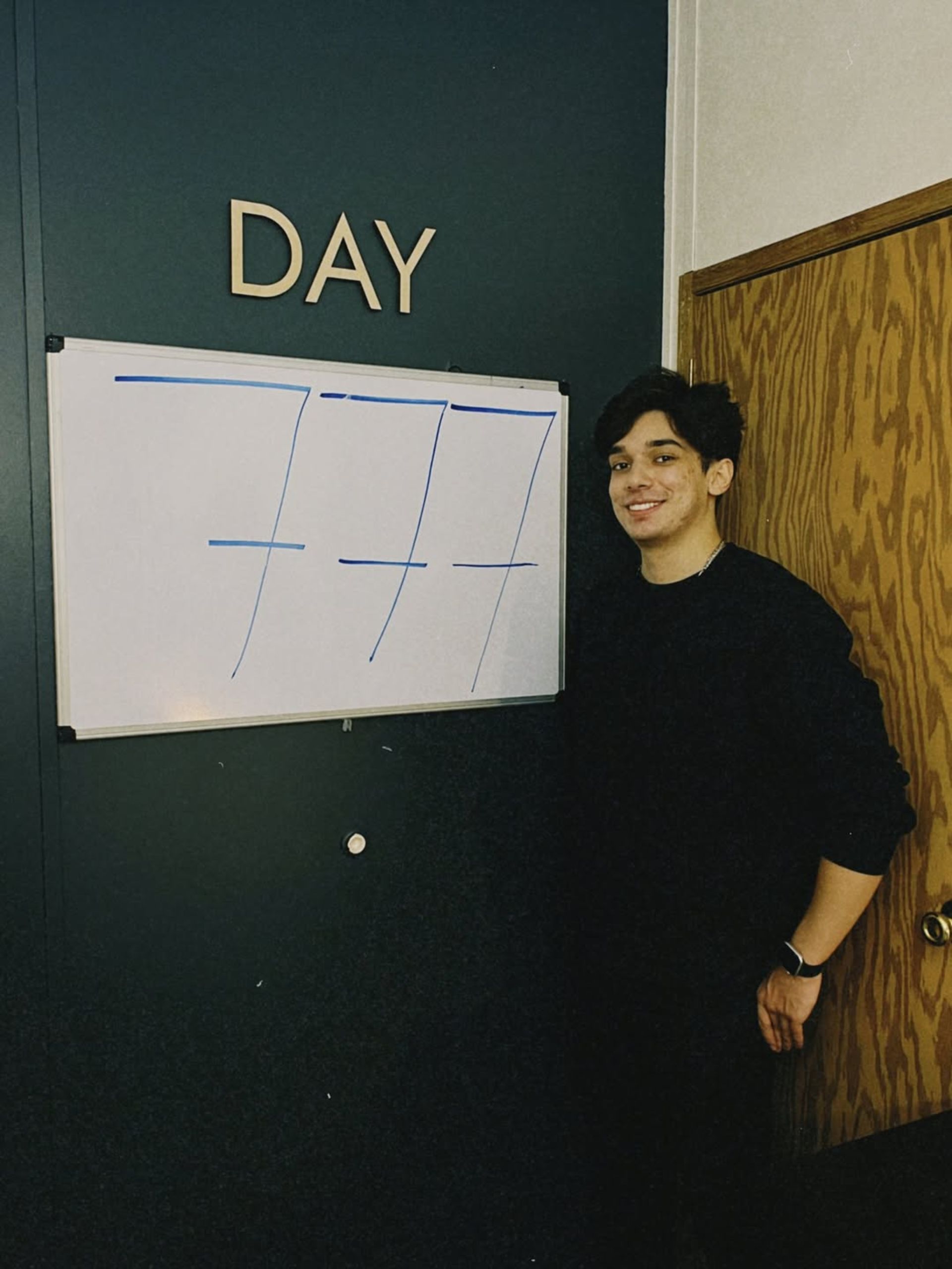 یک پسر جوان با لباس مشکی در حال نمایش عدد روی تخته وایت‌برد