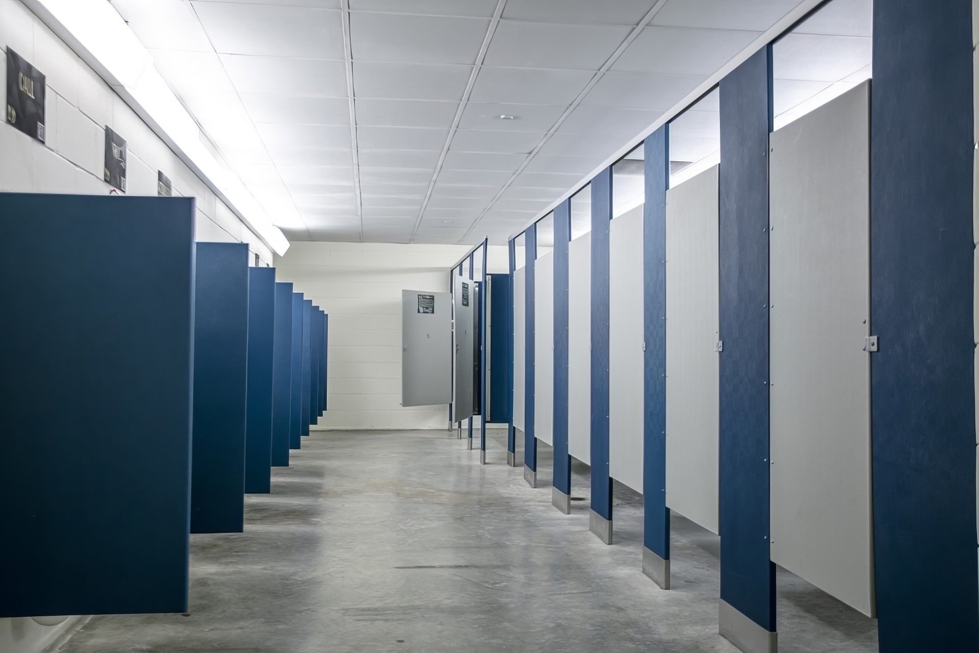 راهرو‌ی سرویس بهداشتی عمومی شامل درهای آبی غرفه‌ها