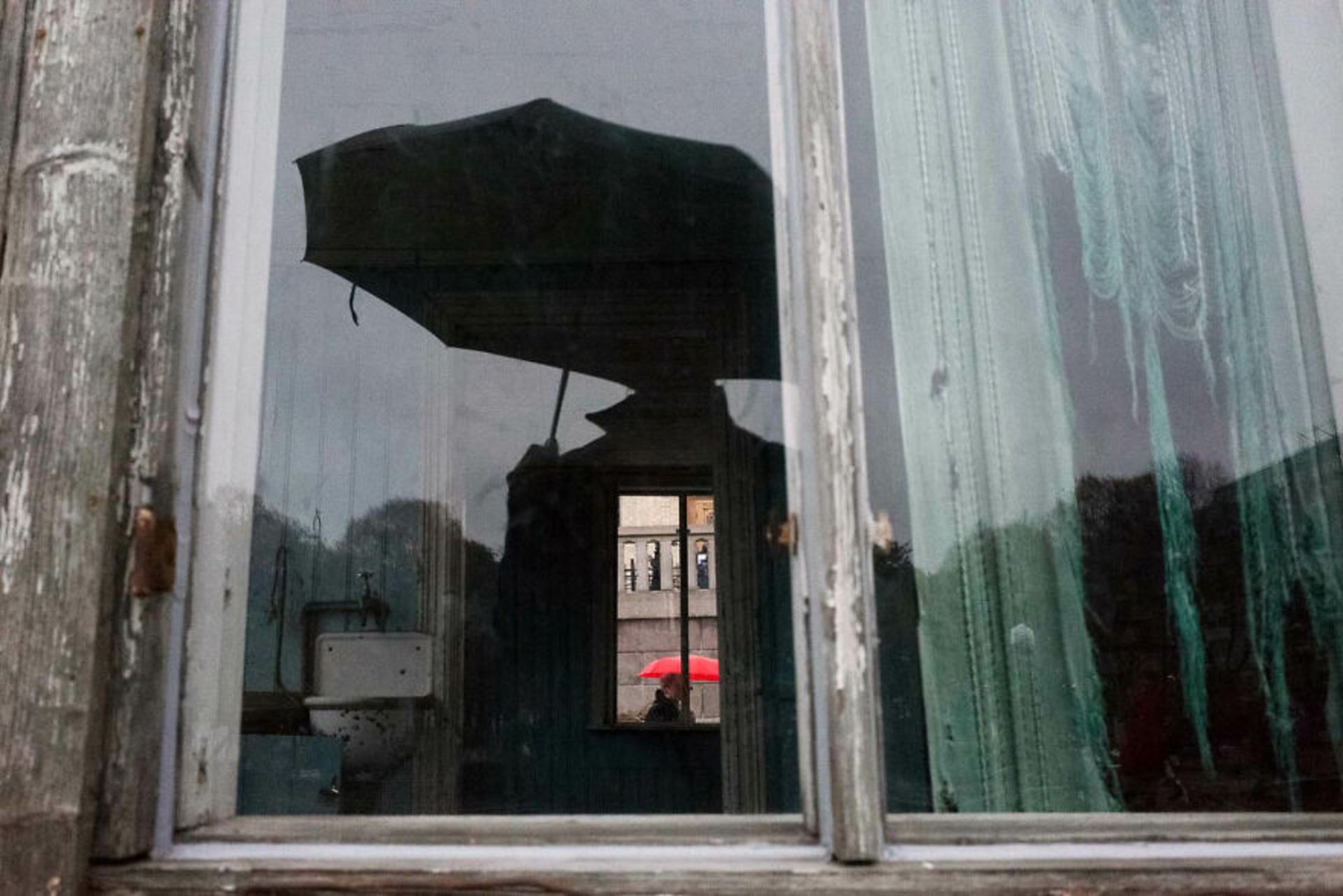 سایه مرد با چتر در پنجره و مردی با چتر قرمز