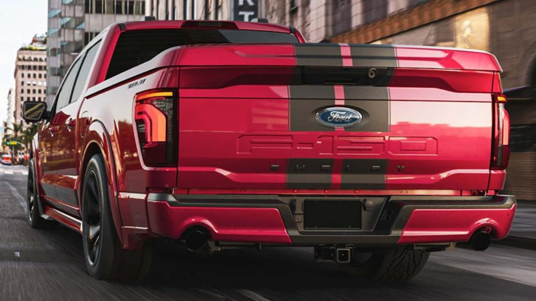 نمای پشت یک وانت قرمز رنگ فورد F-150 مدل شلبی با خطوط سیاه روی بدنه در خیابان شهری.