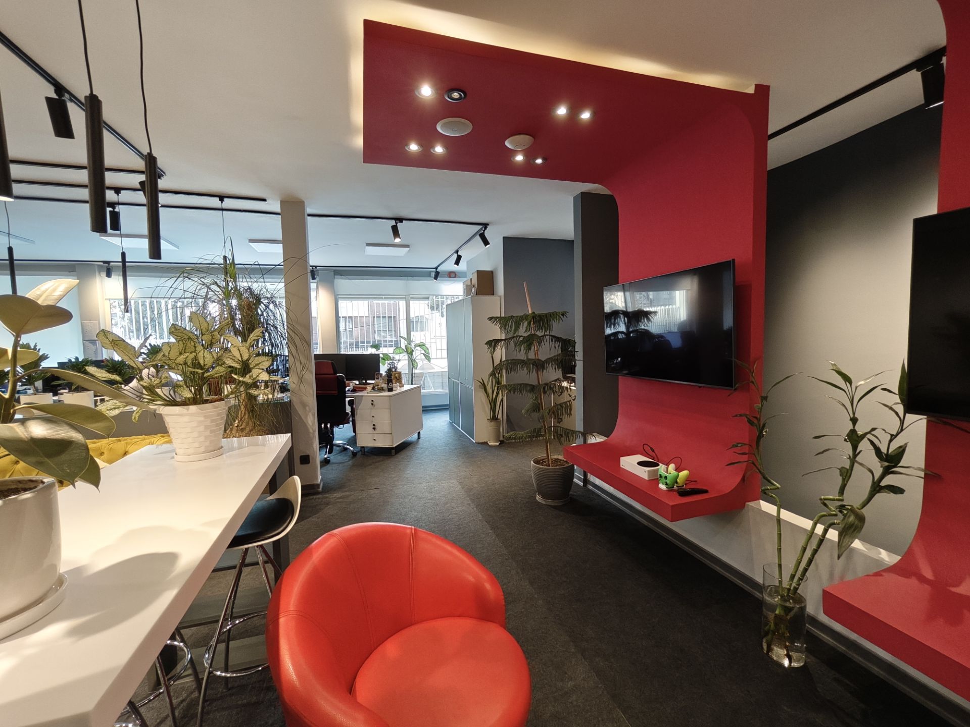 دفترکار زومیت با صندلی به رنگ قرمز و گلدان‌های گل در روبرو