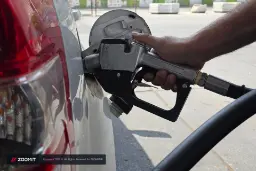 دستِ یک فرد در حال استفاده از نازل پمپ بنزین برای سوخت‌گیری خودرو