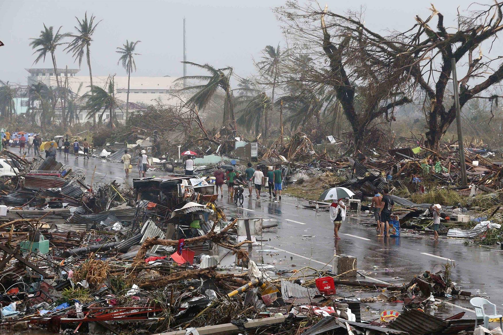 مردم شهر تاکلوبان در فیلیپن در جاده‌ای مملو از آوار پس از طوفان قدم می‌زنند