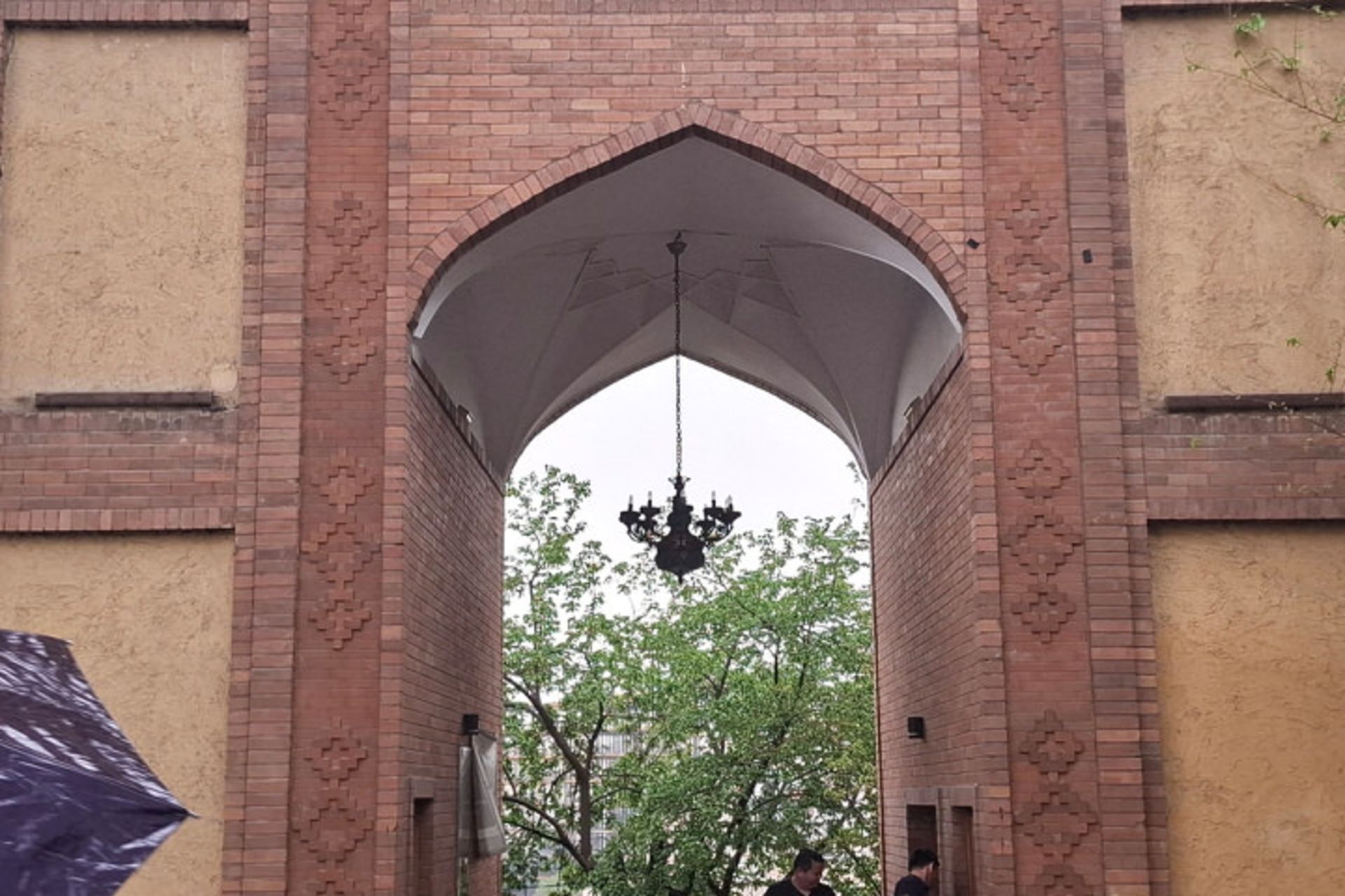 سردر آجری یک دروازه قدیمی در باغی با درختان سرسبز