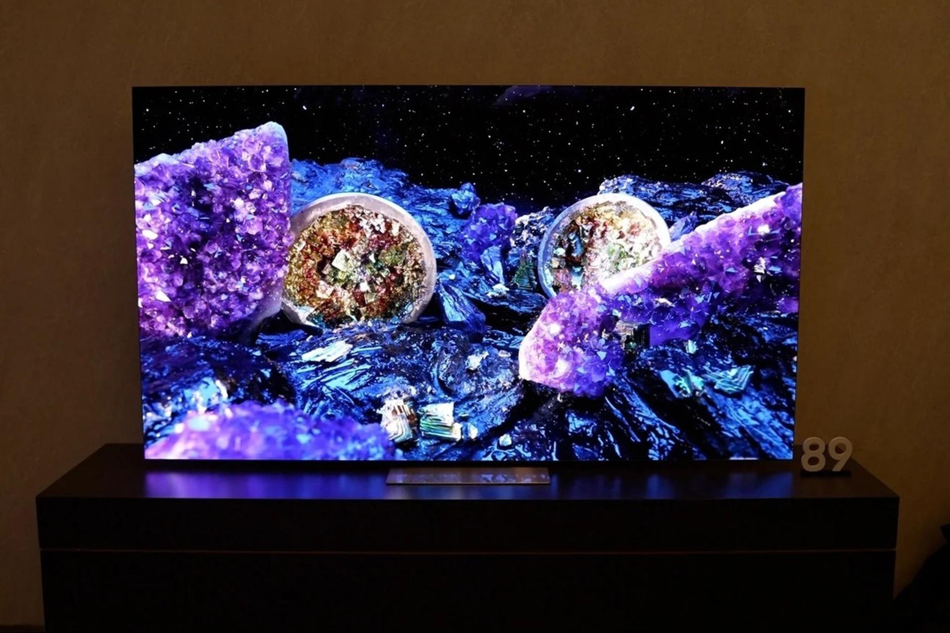 نمای روبرو از تلوزیون QLED 4K QE1C سامسونگ که روی میز تلوزیون چوبی قرار گرفته است
