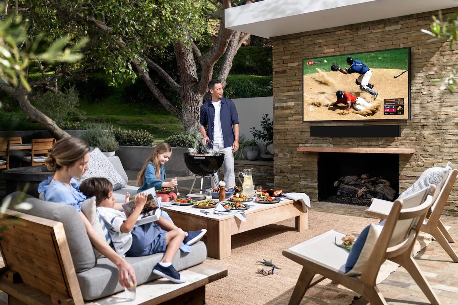 تصویر یک خانواده که در فضای باز روبروی تلویزیون The Terrace سامسونگ نشسته اند